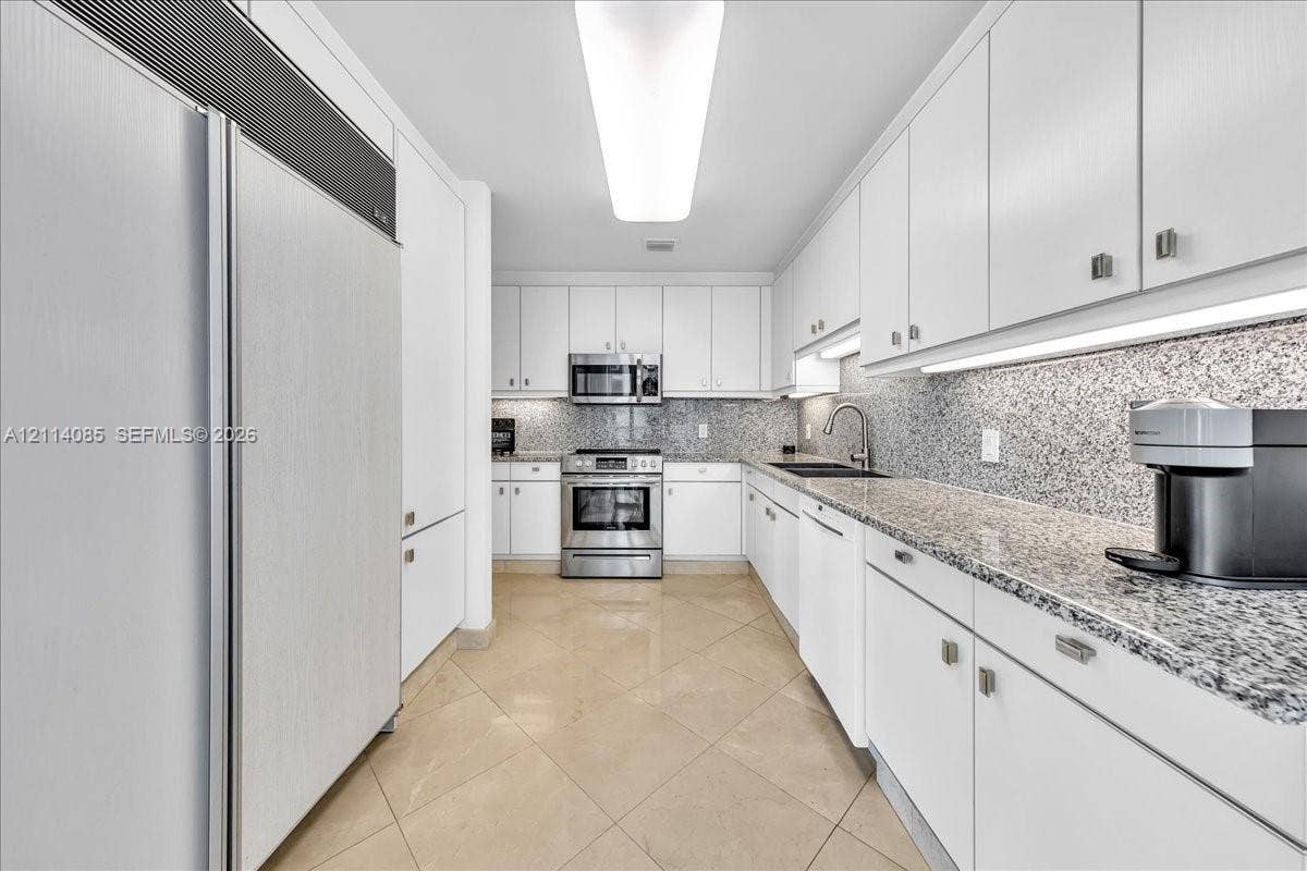 10101 Collins Avenue, #8D, Bal Harbour, FL 33154 Kitchen featuring white cabinetry, stone-finish countertops, stainless steel appliances, under-cabinet lighting, and tile flooring