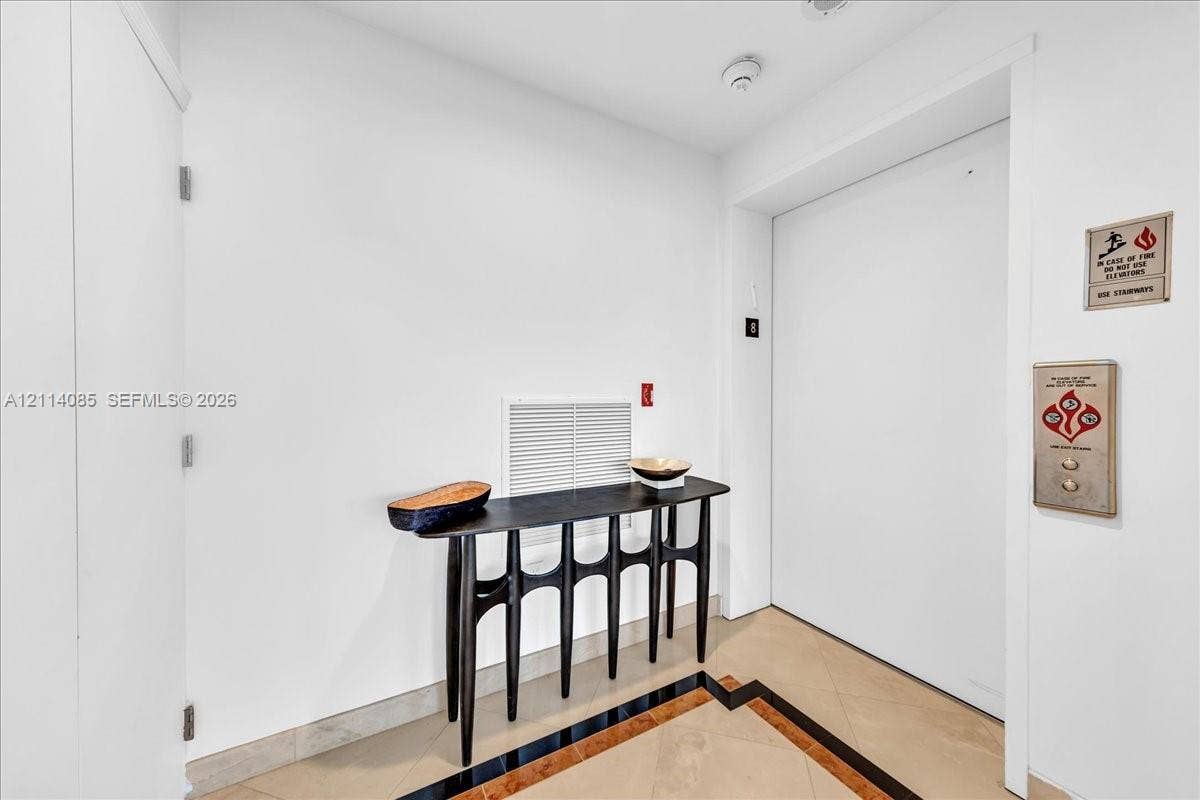10101 Collins Avenue, #8D, Bal Harbour, FL 33154 Elevator landing featuring stone flooring with inlaid border detail and direct elevator access