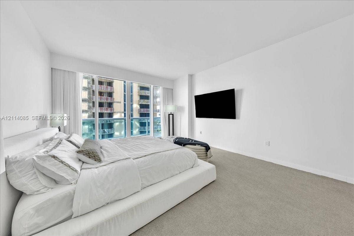 10101 Collins Avenue, #8D, Bal Harbour, FL 33154 Floor-to-ceiling windows, neutral carpet flooring, and wall-mounted television hardware