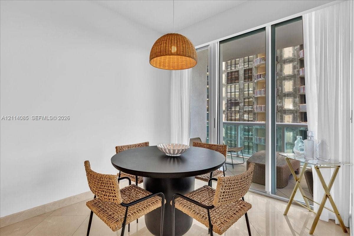 10101 Collins Avenue, #8D, Bal Harbour, FL 33154 Floor-to-ceiling glass sliders, polished stone flooring, and a woven dome pendant light fixture