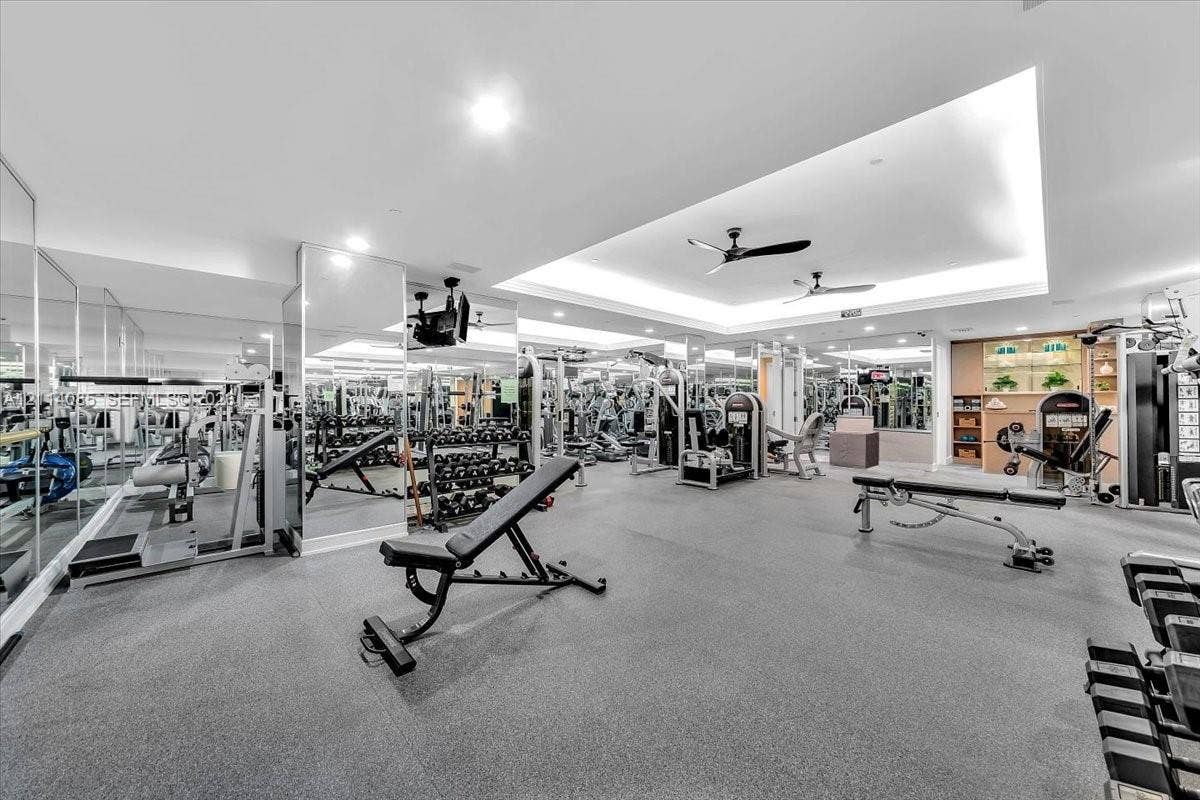 10101 Collins Avenue, #8D, Bal Harbour, FL 33154 Fitness facility featuring floor-to-ceiling mirrors, recessed tray ceiling, integrated ceiling fans, and rubberized flooring