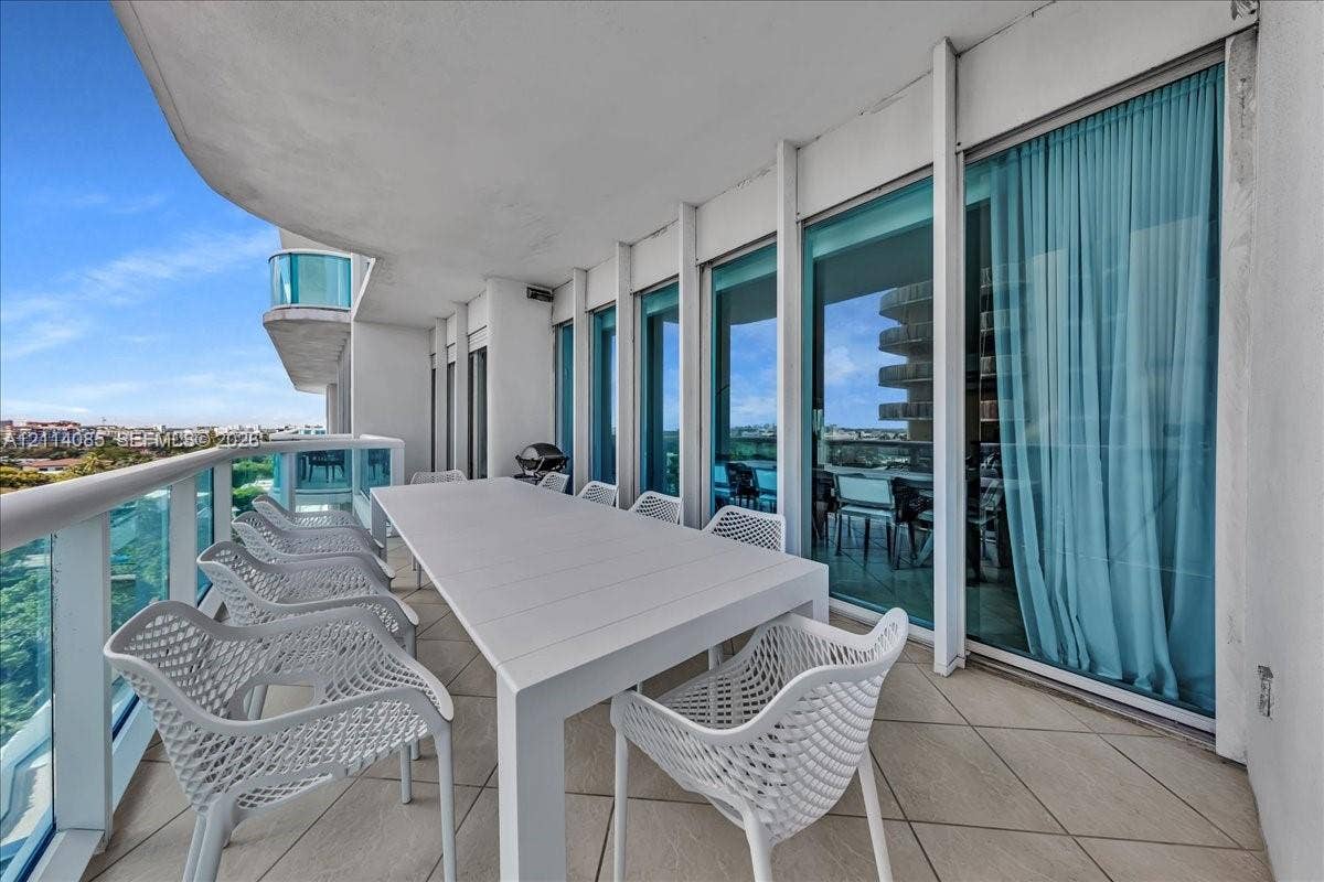 10101 Collins Avenue, #8D, Bal Harbour, FL 33154 Expansive covered balcony with large-format tile flooring, glass panel railings, and floor-to-ceiling glass doors