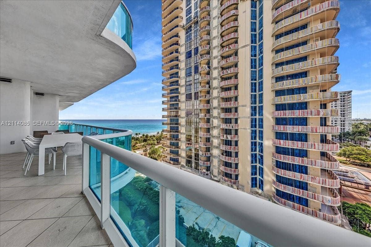 10101 Collins Avenue, #8D, Bal Harbour, FL 33154 Curved private balcony featuring large-format tile flooring and blue glass panel railings