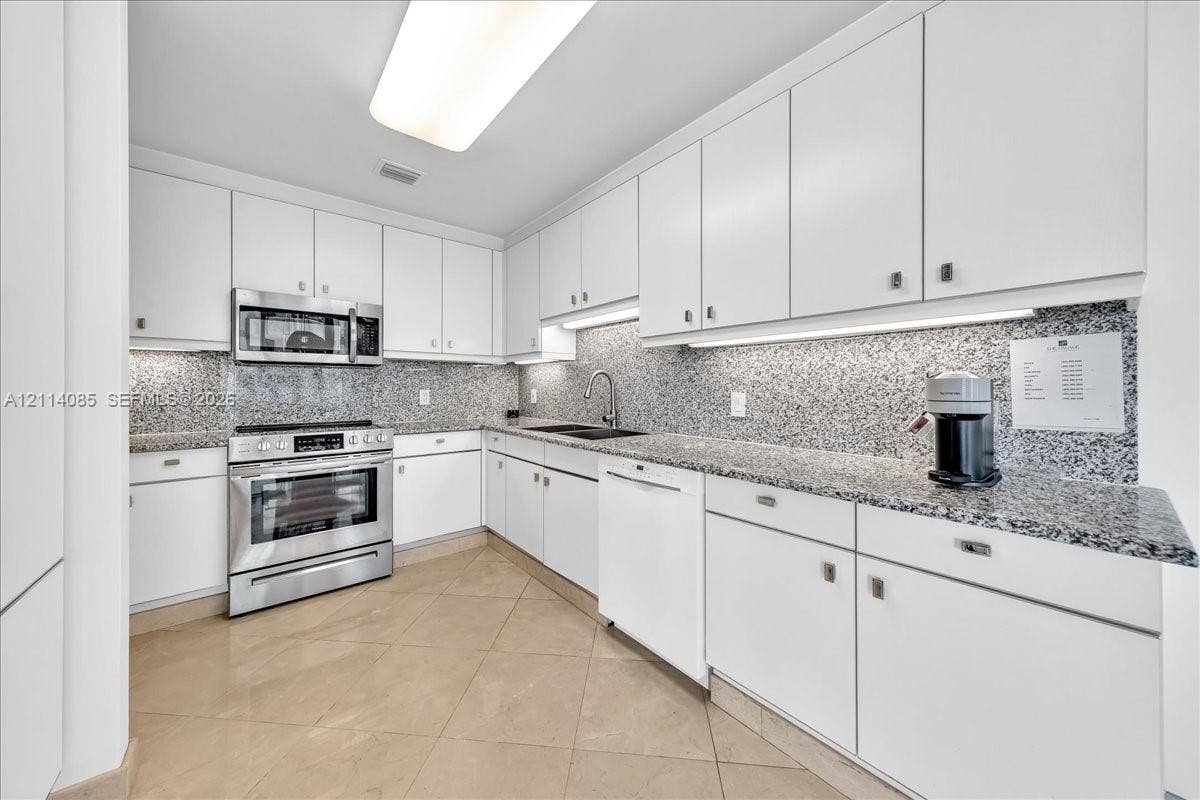 10101 Collins Avenue, #8D, Bal Harbour, FL 33154 Kitchen featuring white cabinetry, stone-finish countertops, full-height backsplash, stainless steel appliances, and tile flooring