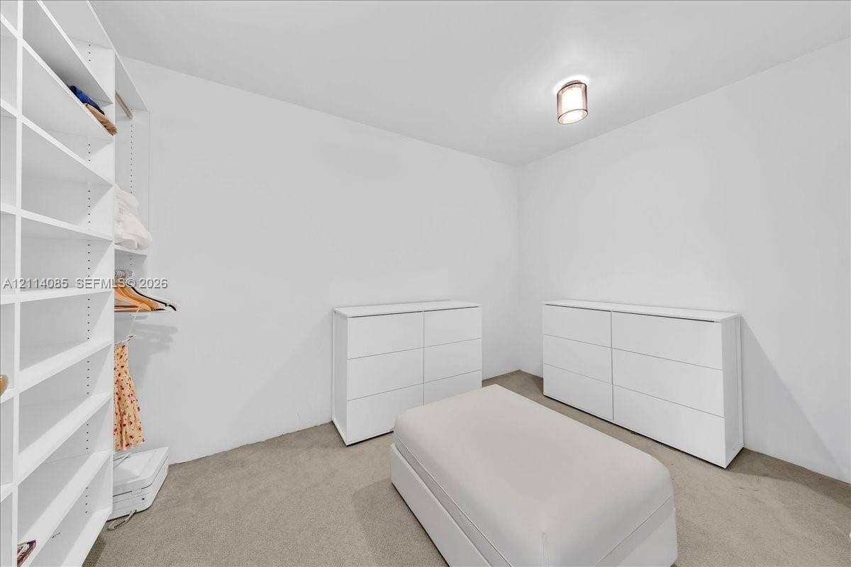 10101 Collins Avenue, #8D, Bal Harbour, FL 33154 Custom built-in white shelving system with integrated hanging rods and flush-mount ceiling lighting