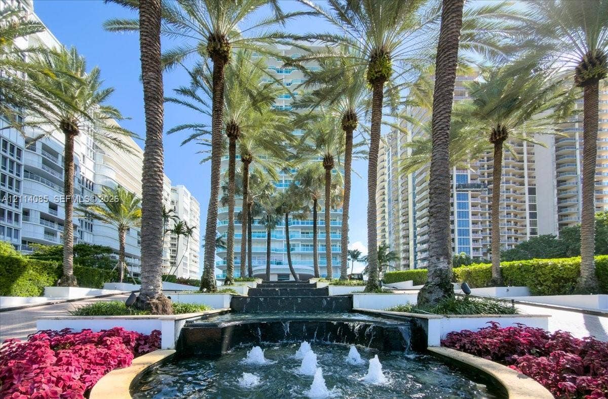 10101 Collins Avenue, #8D, Bal Harbour, FL 33154 Tiered stone water feature, mature palm trees, and manicured landscaping with floral beds