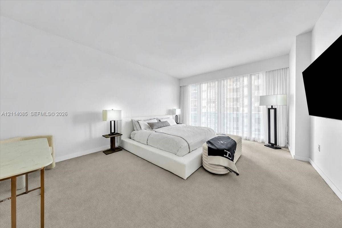 10101 Collins Avenue, #8D, Bal Harbour, FL 33154 Expansive room featuring wall-to-wall carpeting, high ceilings, and floor-to-ceiling windows with full-length window treatments