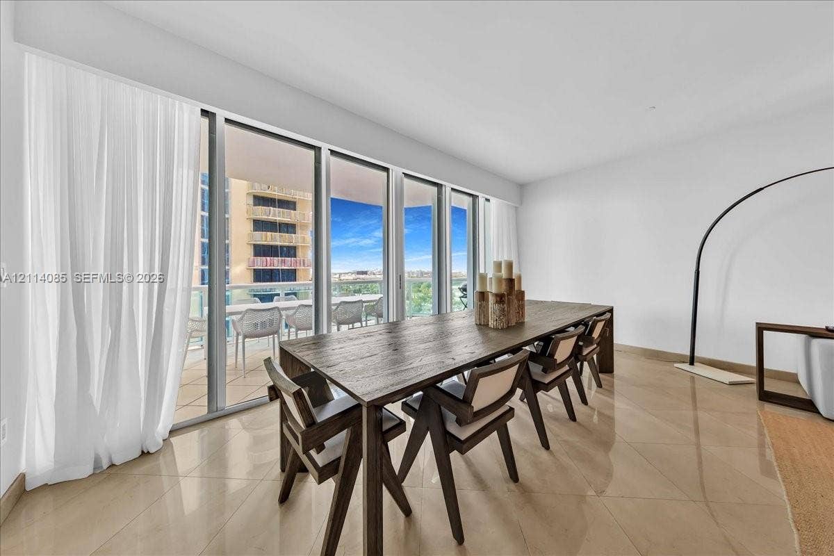 10101 Collins Avenue, #8D, Bal Harbour, FL 33154 Floor-to-ceiling glass sliding doors, private balcony with glass railing, large-format tile flooring, and neutral wall finishes