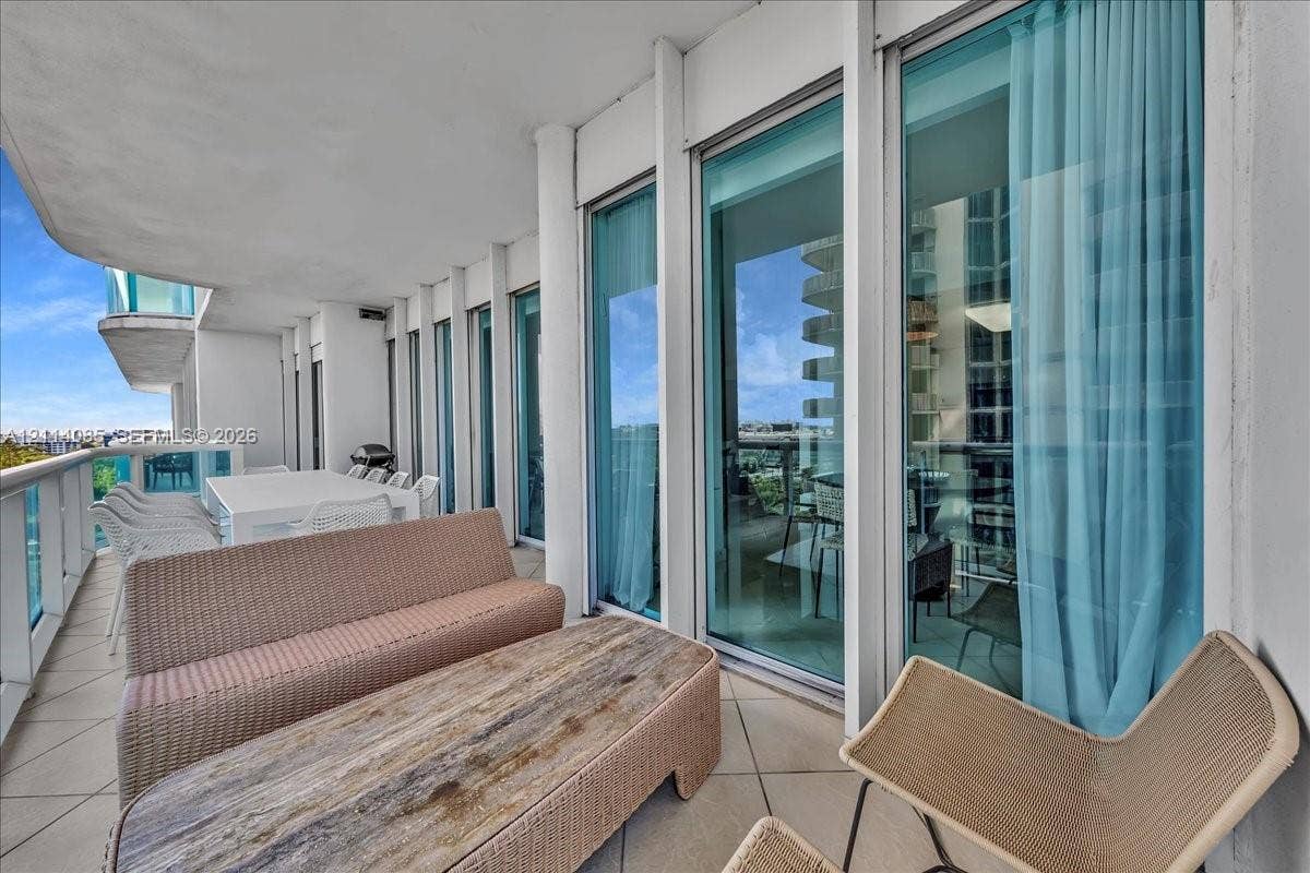10101 Collins Avenue, #8D, Bal Harbour, FL 33154 Expansive covered balcony featuring large-format tile flooring, vertical structural columns, and full-height glass sliding doors