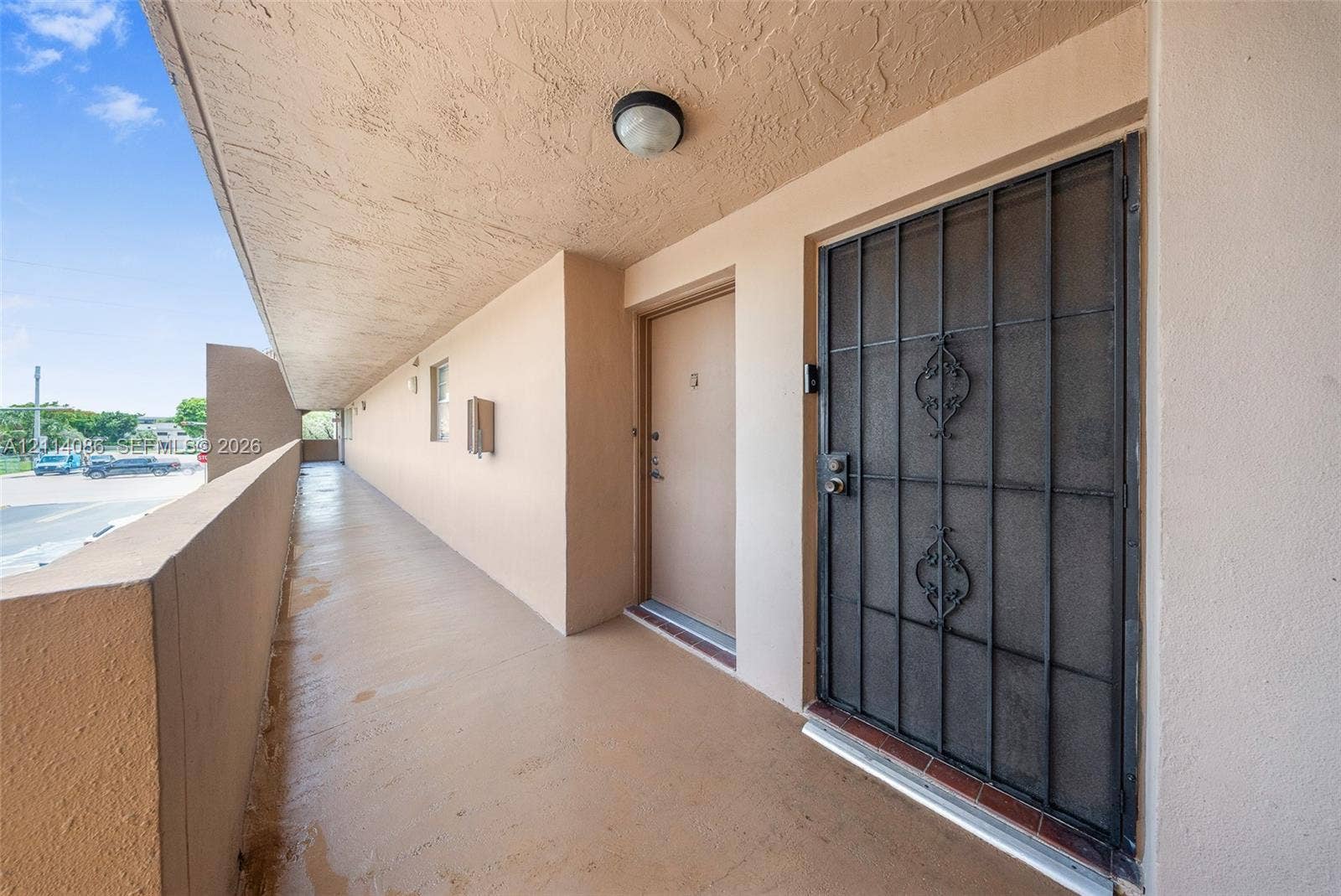 706 NW 87th Avenue, #204, Miami, Miami, FL 33172 Covered exterior walkway featuring a protective metal security door, recessed ceiling lighting, and solid surface flooring