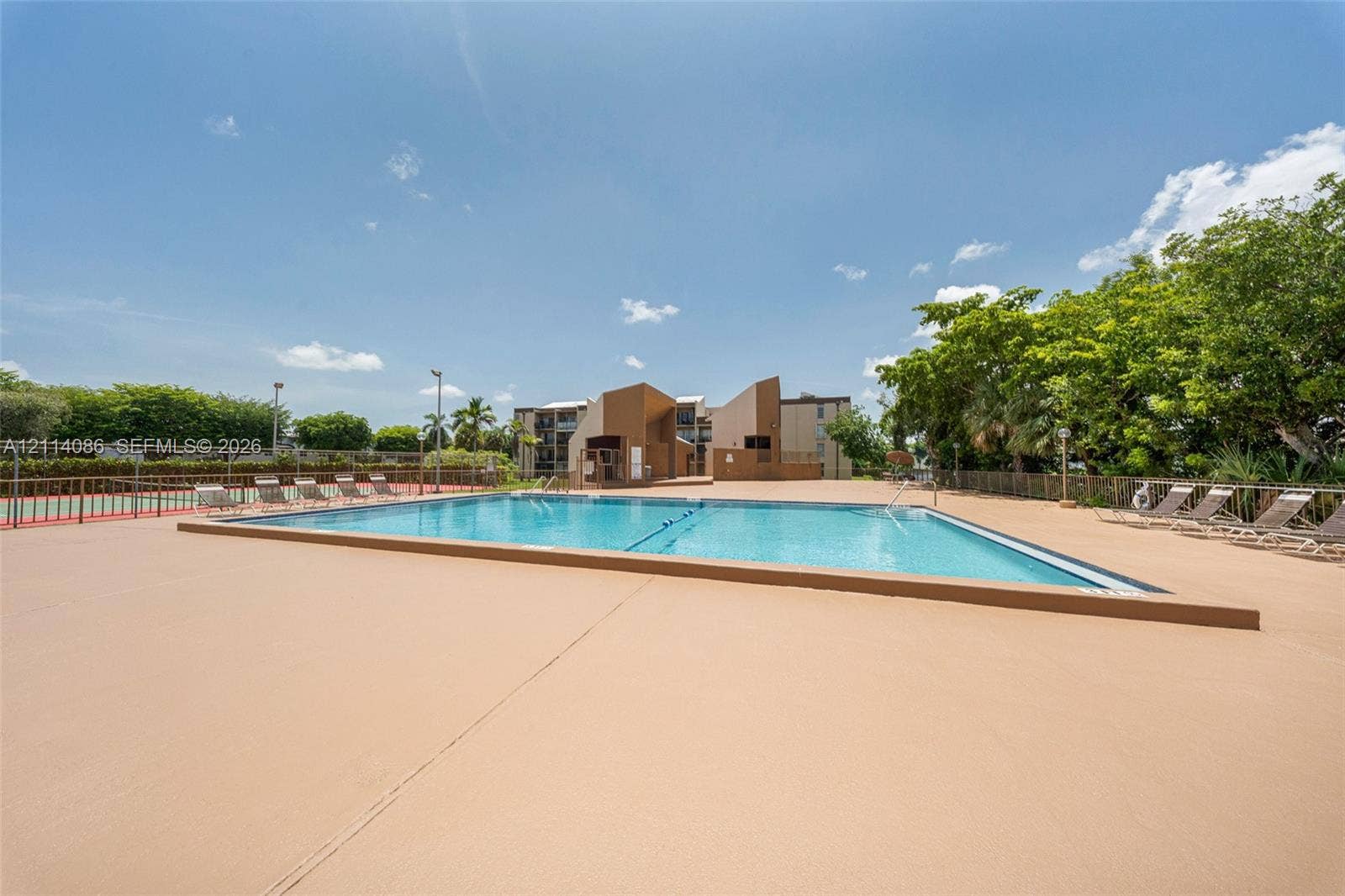 706 NW 87th Avenue, #204, Miami, Miami, FL 33172 Swimming pool featuring a concrete deck, metal perimeter fencing, and surrounding mature trees