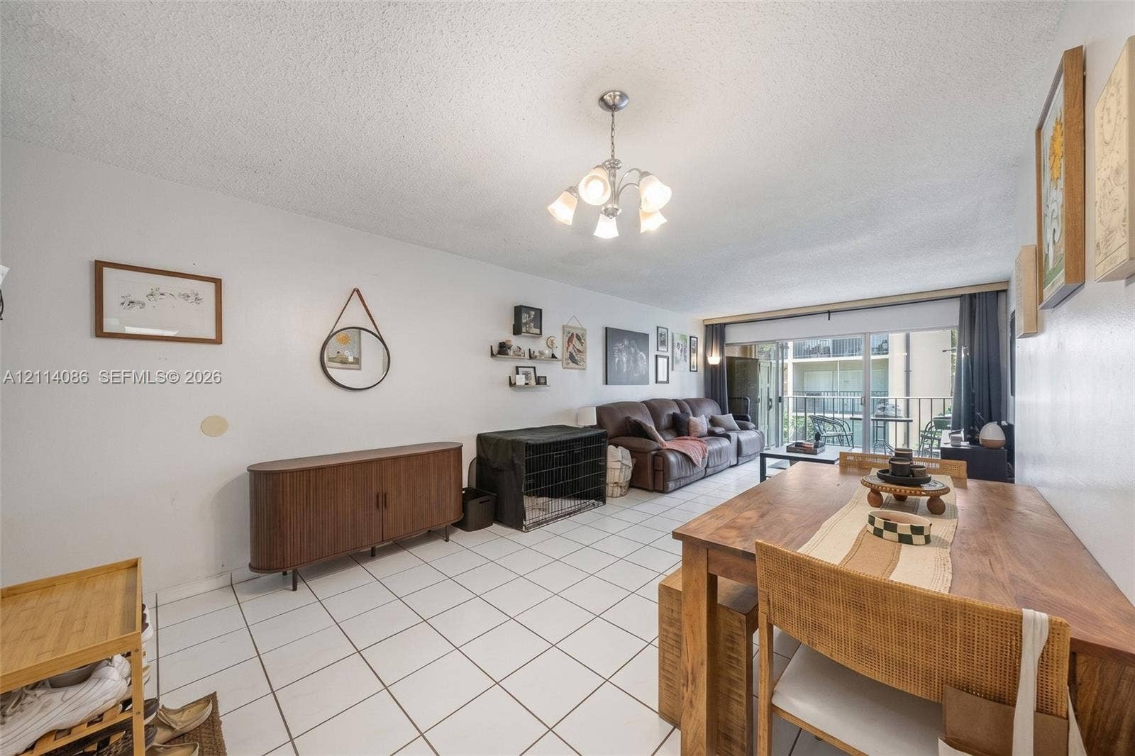706 NW 87th Avenue, #204, Miami, Miami, FL 33172 Open-concept floor plan featuring tile flooring, a multi-arm chandelier, and sliding glass doors providing outdoor access