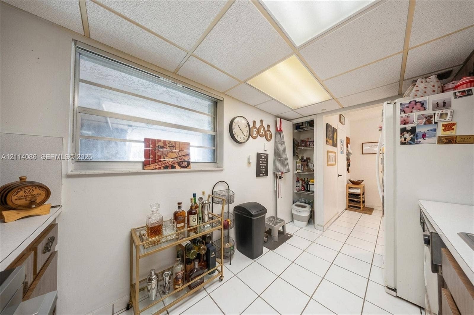 706 NW 87th Avenue, #204, Miami, Miami, FL 33172 Kitchen featuring white tile flooring, drop ceiling with integrated lighting, slider window, and built-in pantry cabinetry