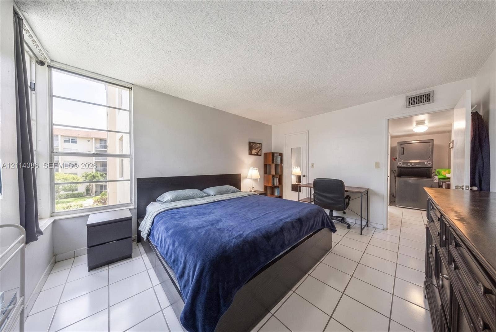 706 NW 87th Avenue, #204, Miami, Miami, FL 33172 Large format window with grid detailing, ceramic tile flooring, and dedicated laundry area featuring a stacked washer and dryer