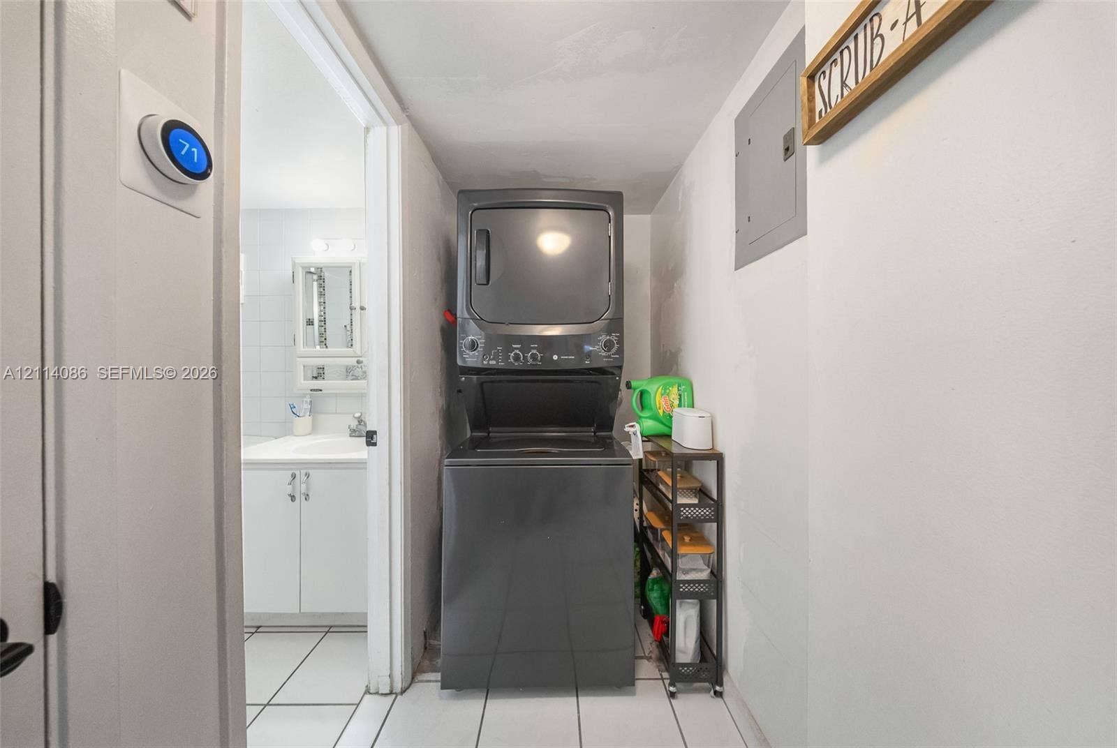706 NW 87th Avenue, #204, Miami, Miami, FL 33172 Laundry area featuring a stackable washer and dryer, tile flooring, and a wall-mounted programmable thermostat