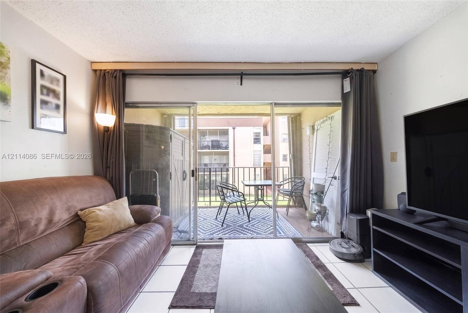 706 NW 87th Avenue, #204, Miami, Miami, FL 33172 Living area featuring large format tile flooring and floor-to-ceiling sliding glass doors opening to a private balcony with metal railing