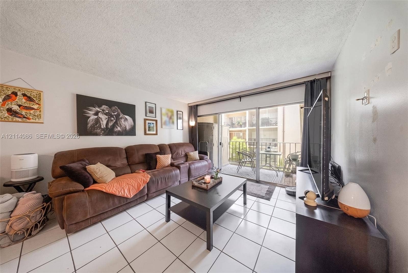 706 NW 87th Avenue, #204, Miami, Miami, FL 33172 Living area featuring ceramic tile flooring and floor-to-ceiling sliding glass doors providing access to a private balcony
