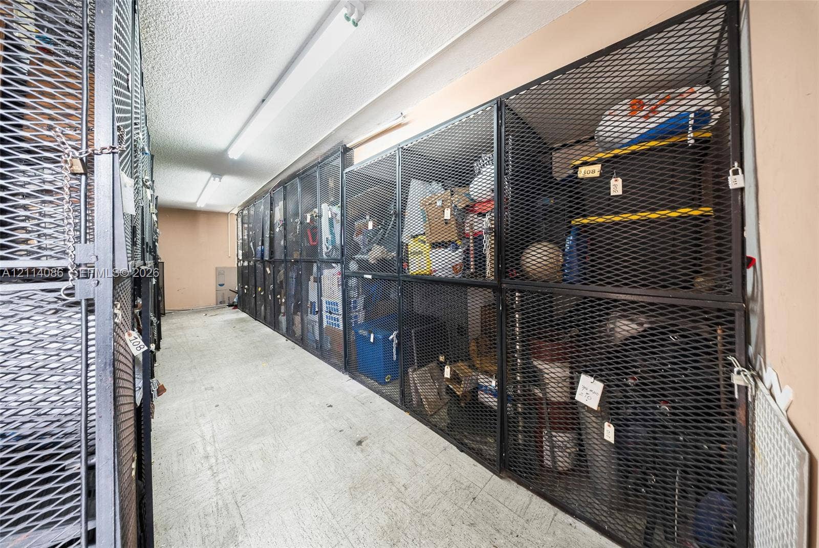 706 NW 87th Avenue, #204, Miami, Miami, FL 33172 Dedicated storage room featuring floor-to-ceiling metal mesh enclosures and linear fluorescent lighting