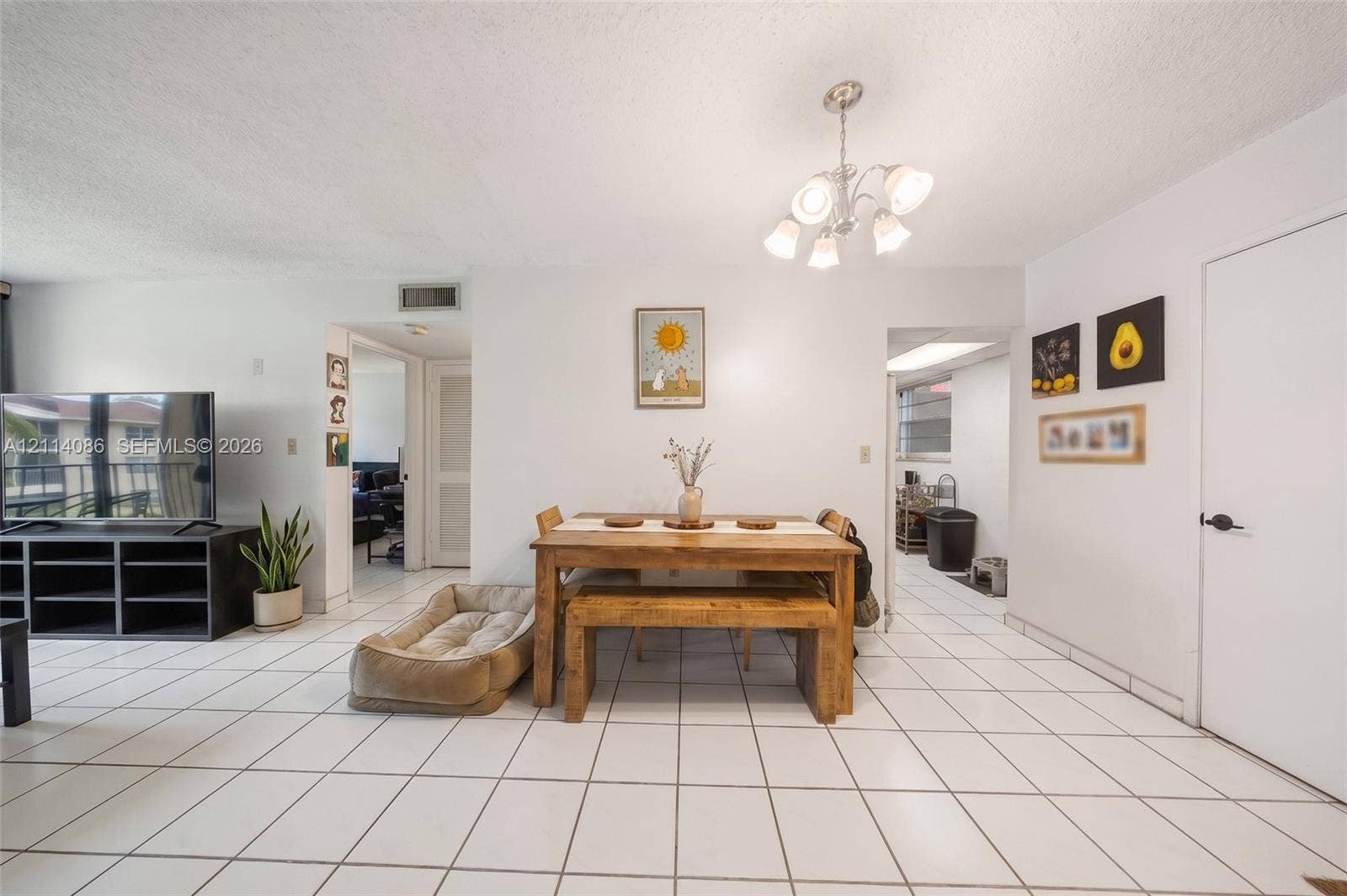 706 NW 87th Avenue, #204, Miami, Miami, FL 33172 Open living space featuring light-colored tile flooring, neutral wall finishes, and a multi-arm chandelier