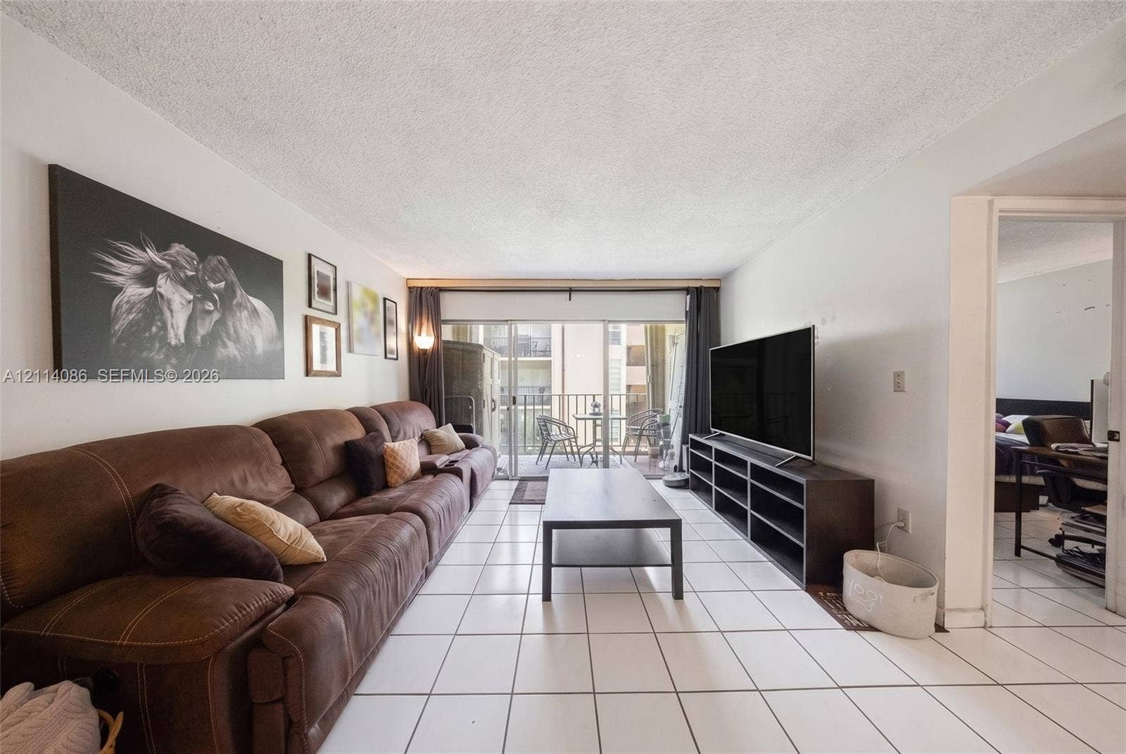 706 NW 87th Avenue, #204, Miami, Miami, FL 33172 Living area featuring large-format ceramic tile flooring and sliding glass doors providing access to an exterior balcony