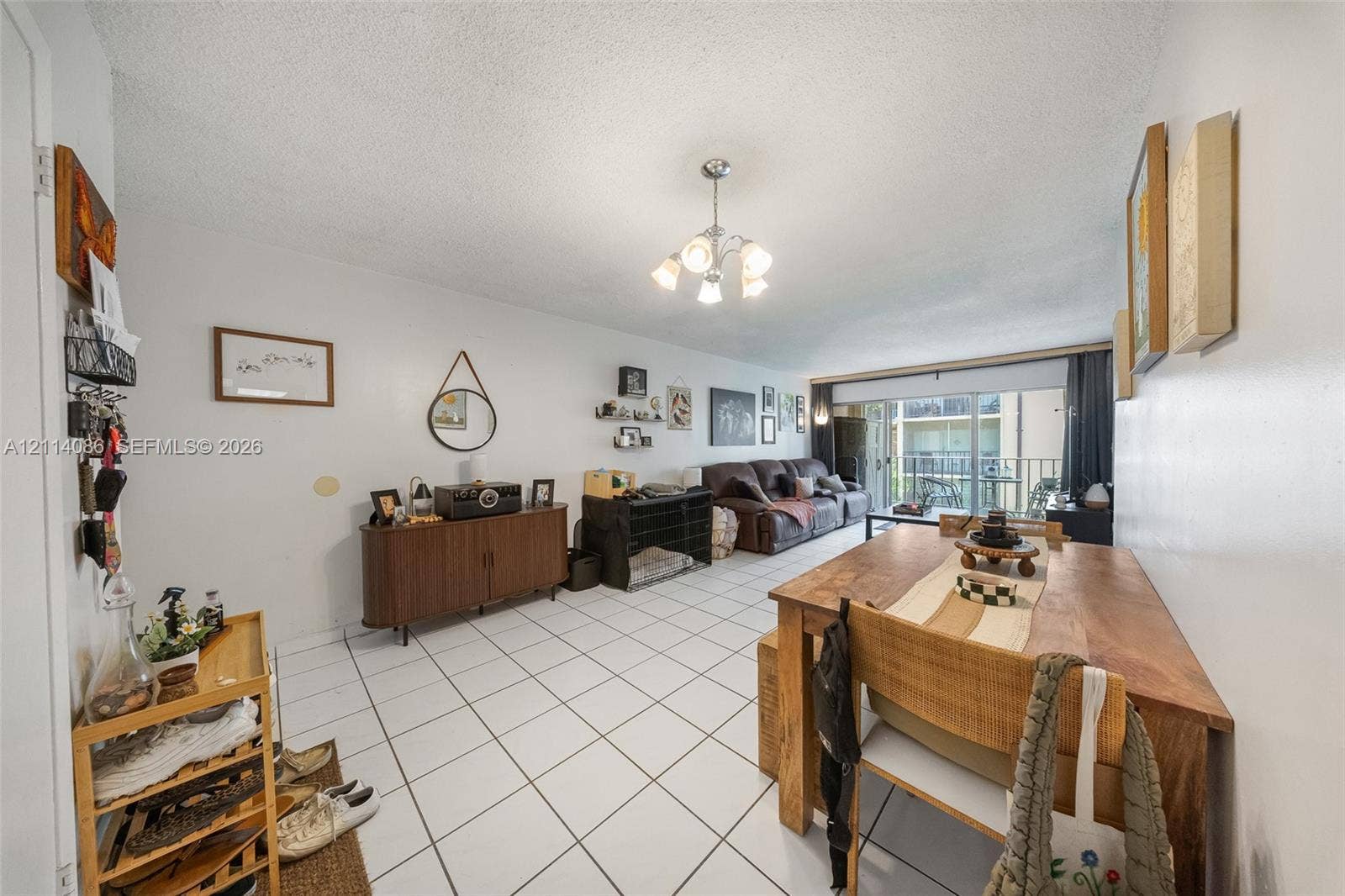 706 NW 87th Avenue, #204, Miami, Miami, FL 33172 Open-concept room featuring white ceramic tile flooring, a multi-arm chandelier, and sliding glass doors with direct exterior access