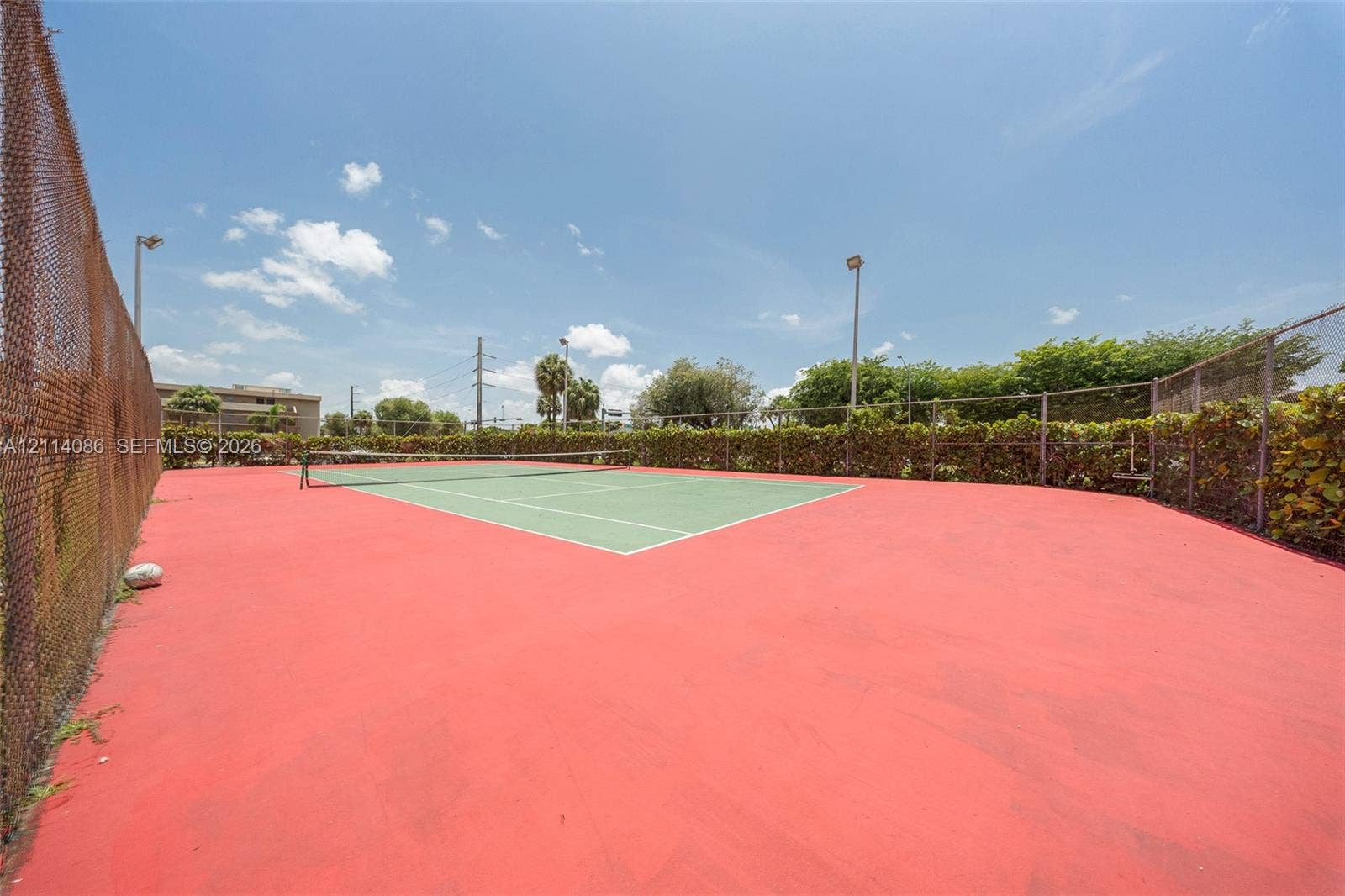 706 NW 87th Avenue, #204, Miami, Miami, FL 33172 Private tennis court featuring a hard surface, perimeter chain-link fencing, and integrated lighting poles