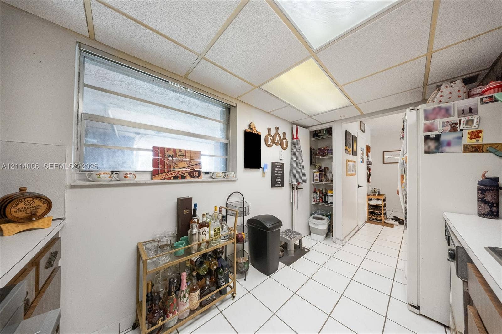 706 NW 87th Avenue, #204, Miami, Miami, FL 33172 Kitchen featuring white tile flooring, drop ceiling panels, horizontal slider window, and built-in pantry storage