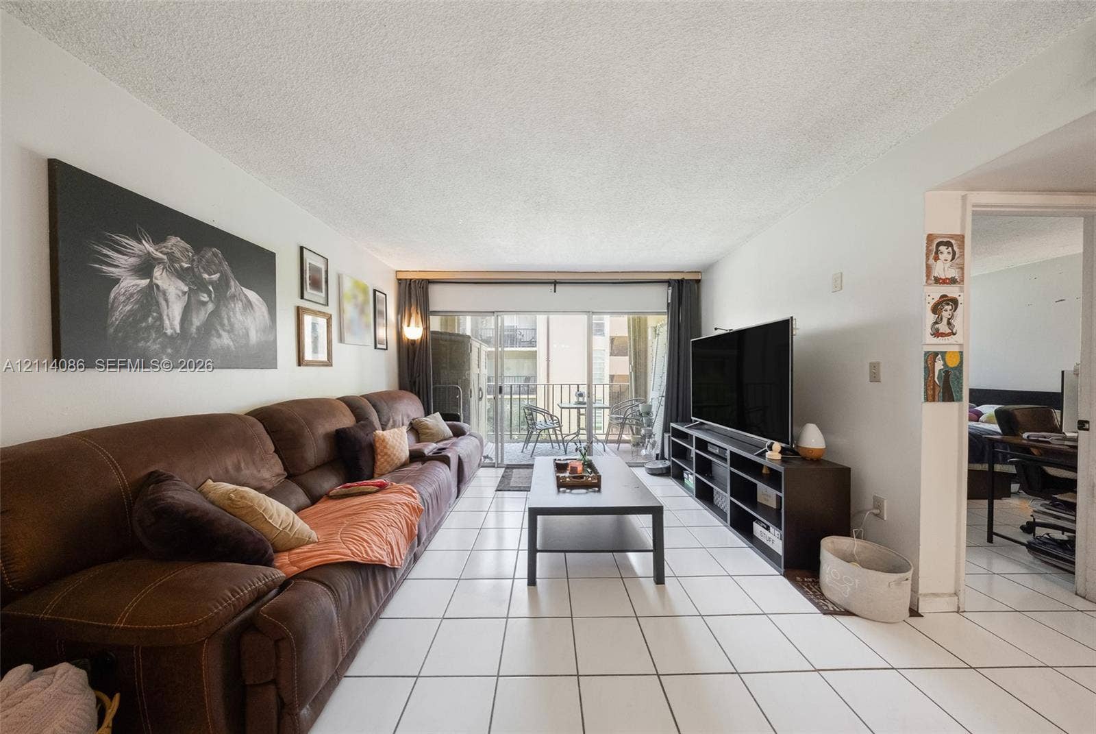 706 NW 87th Avenue, #204, Miami, Miami, FL 33172 Living area featuring white ceramic tile flooring and sliding glass doors with access to an exterior balcony