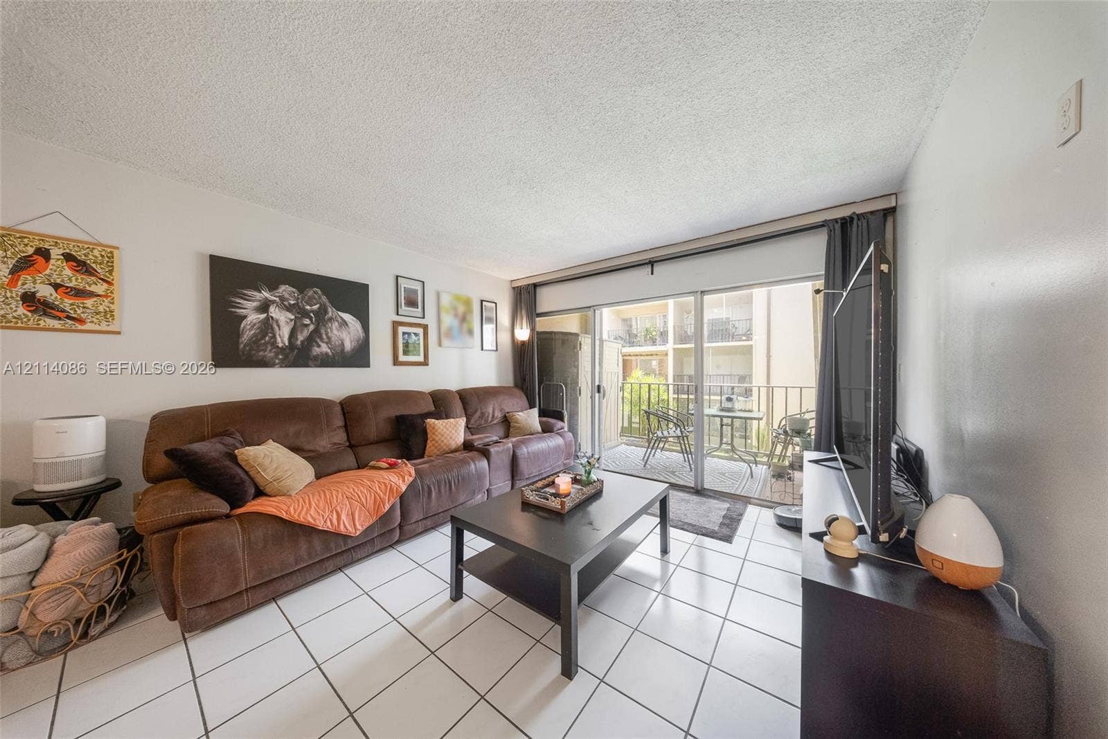 706 NW 87th Avenue, #204, Miami, Miami, FL 33172 Living area featuring white ceramic tile flooring and sliding glass doors with access to an exterior balcony