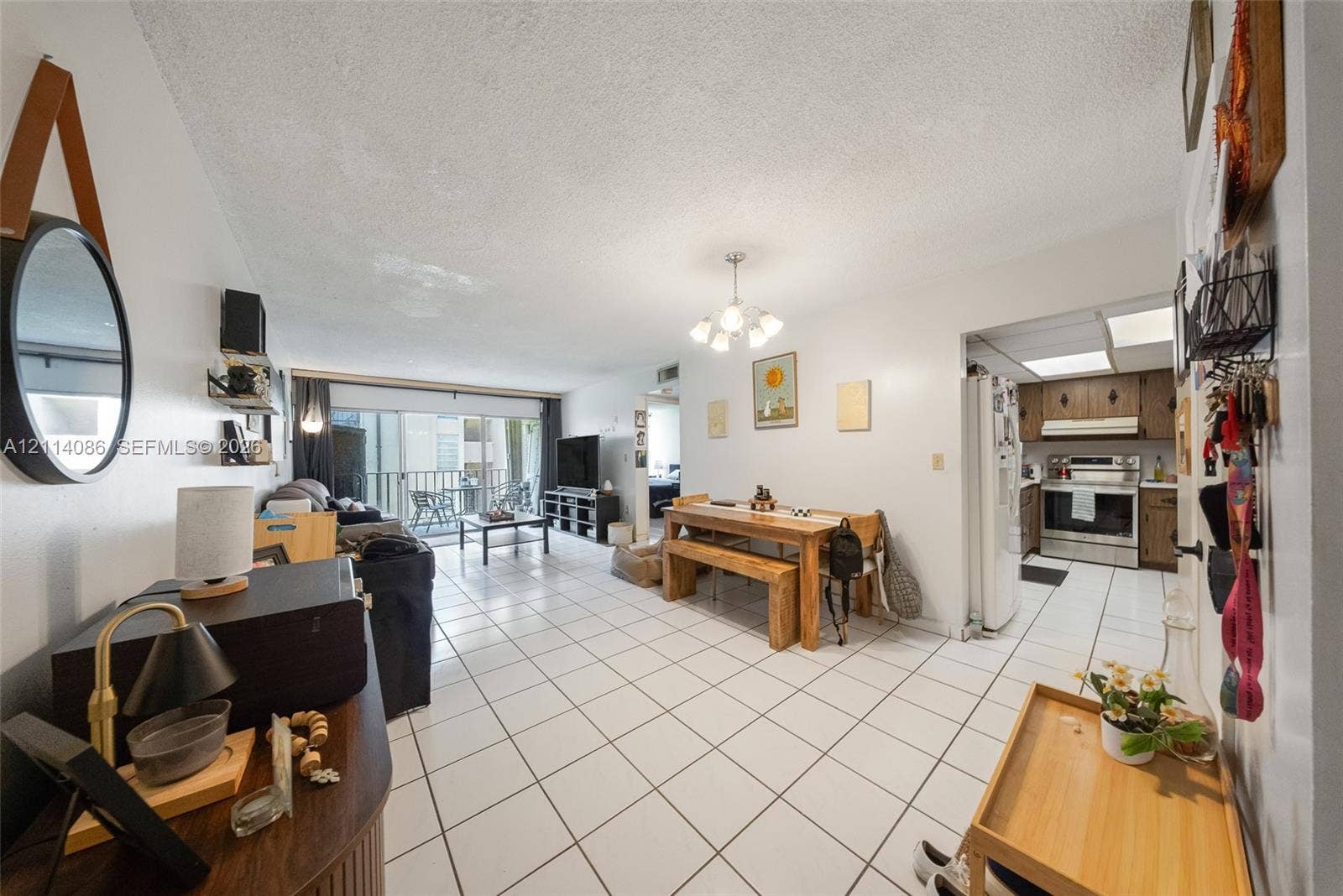 706 NW 87th Avenue, #204, Miami, Miami, FL 33172 Open-concept floor plan featuring tile flooring, a multi-light chandelier, and a sliding glass door providing external access