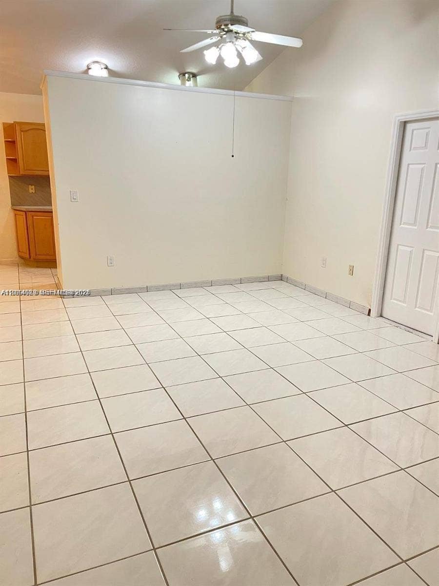 17220 SW 93rd Avenue, #0, Palmetto Bay, Palmetto Bay, FL 33157 Neutral-toned interior featuring high ceilings, white tiled flooring, a ceiling fan with multi-light fixture, and wood-finish cabinetry