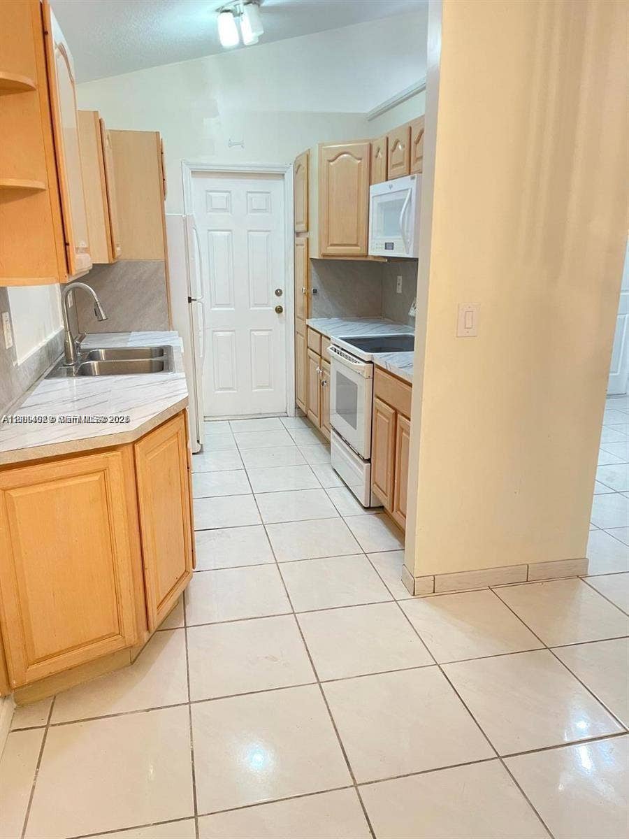 17220 SW 93rd Avenue, #0, Palmetto Bay, Palmetto Bay, FL 33157 Kitchen featuring light wood cabinetry, stone-finish countertops, stainless steel dual-basin sink with arched faucet, ceramic tile flooring, and integrated white appliances