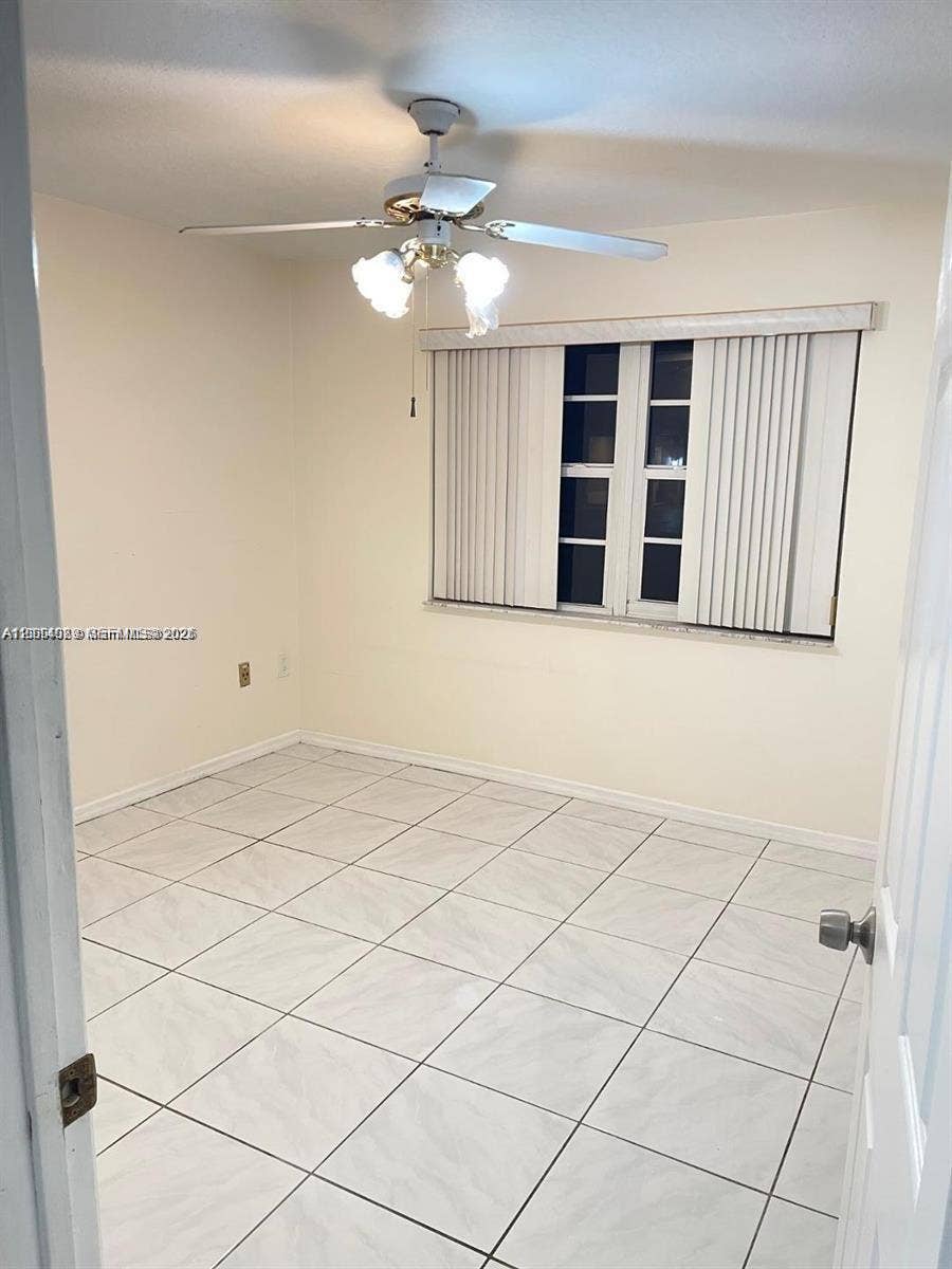 17220 SW 93rd Avenue, #0, Palmetto Bay, Palmetto Bay, FL 33157 Neutral-toned interior featuring large-format tile flooring, a multi-blade ceiling fan with integrated lighting, and vertical window blinds