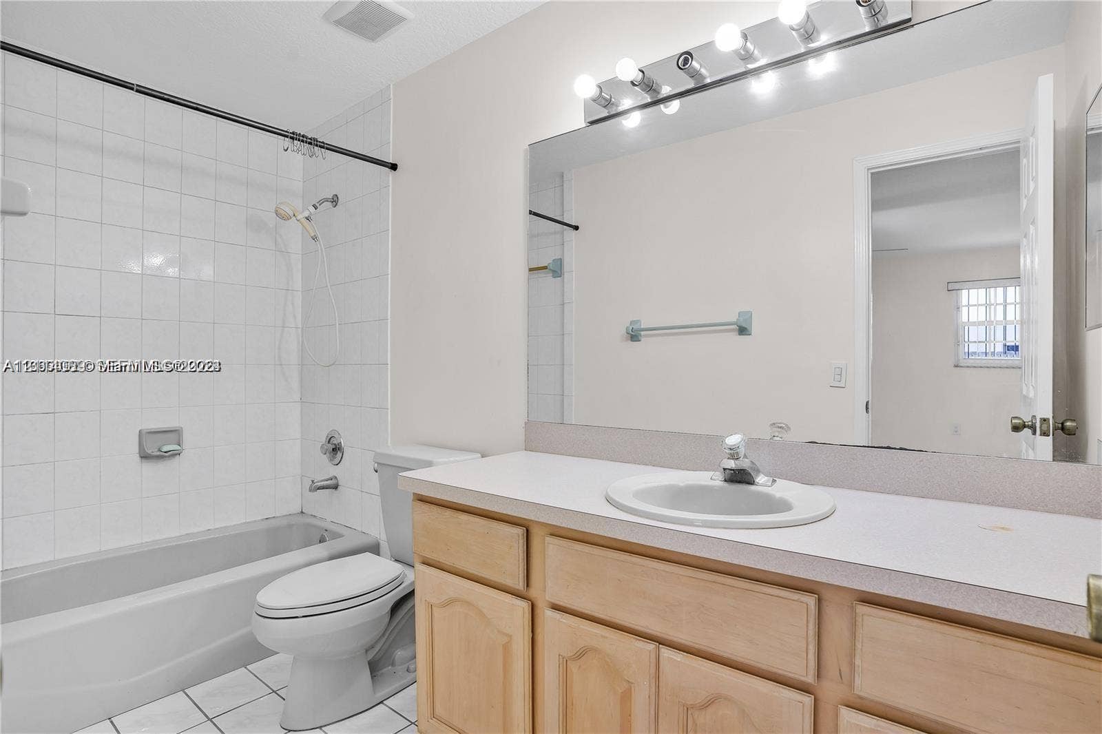 17220 SW 93rd Avenue, #0, Palmetto Bay, Palmetto Bay, FL 33157 Bathroom featuring wood-finish cabinetry, a large wall-mounted vanity mirror, a drop-in sink, and a shower-tub combination with tiled surround