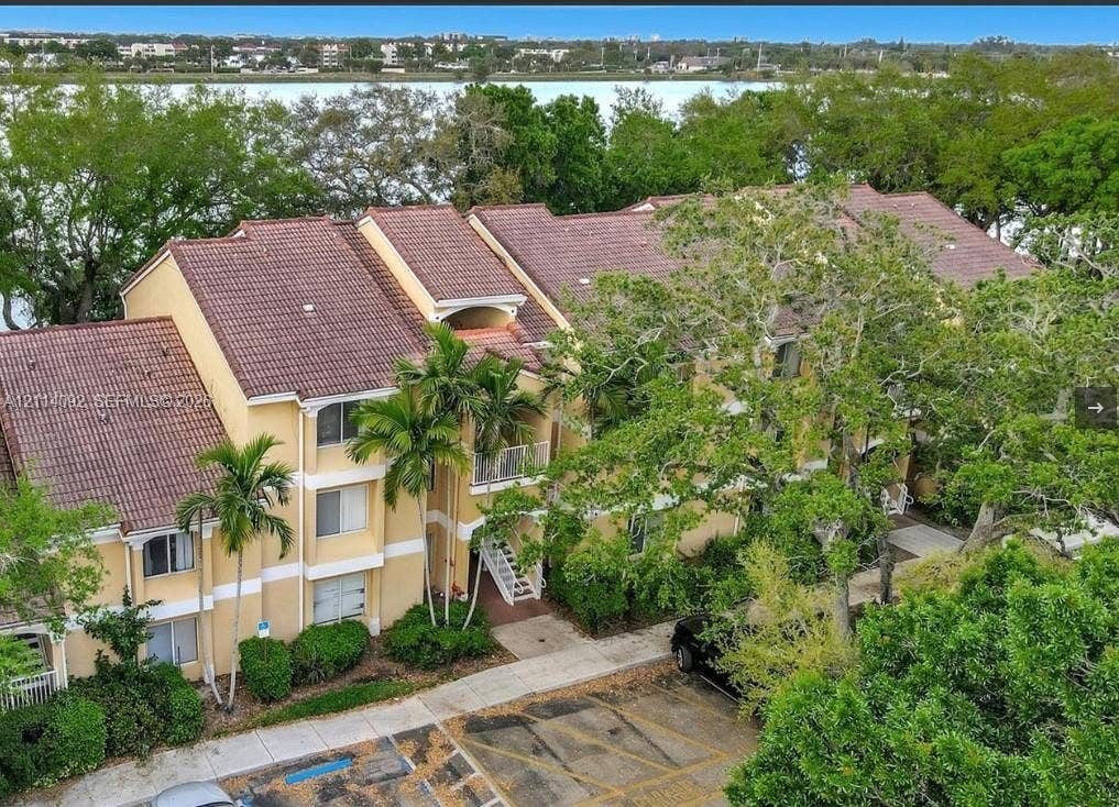 2667 NW 33rd Street, #2413, Oakland Park, Oakland Park, FL 33309 Multi-story residential building featuring a tile roof, stucco exterior, private balconies, and mature landscaping, situated along a waterfront