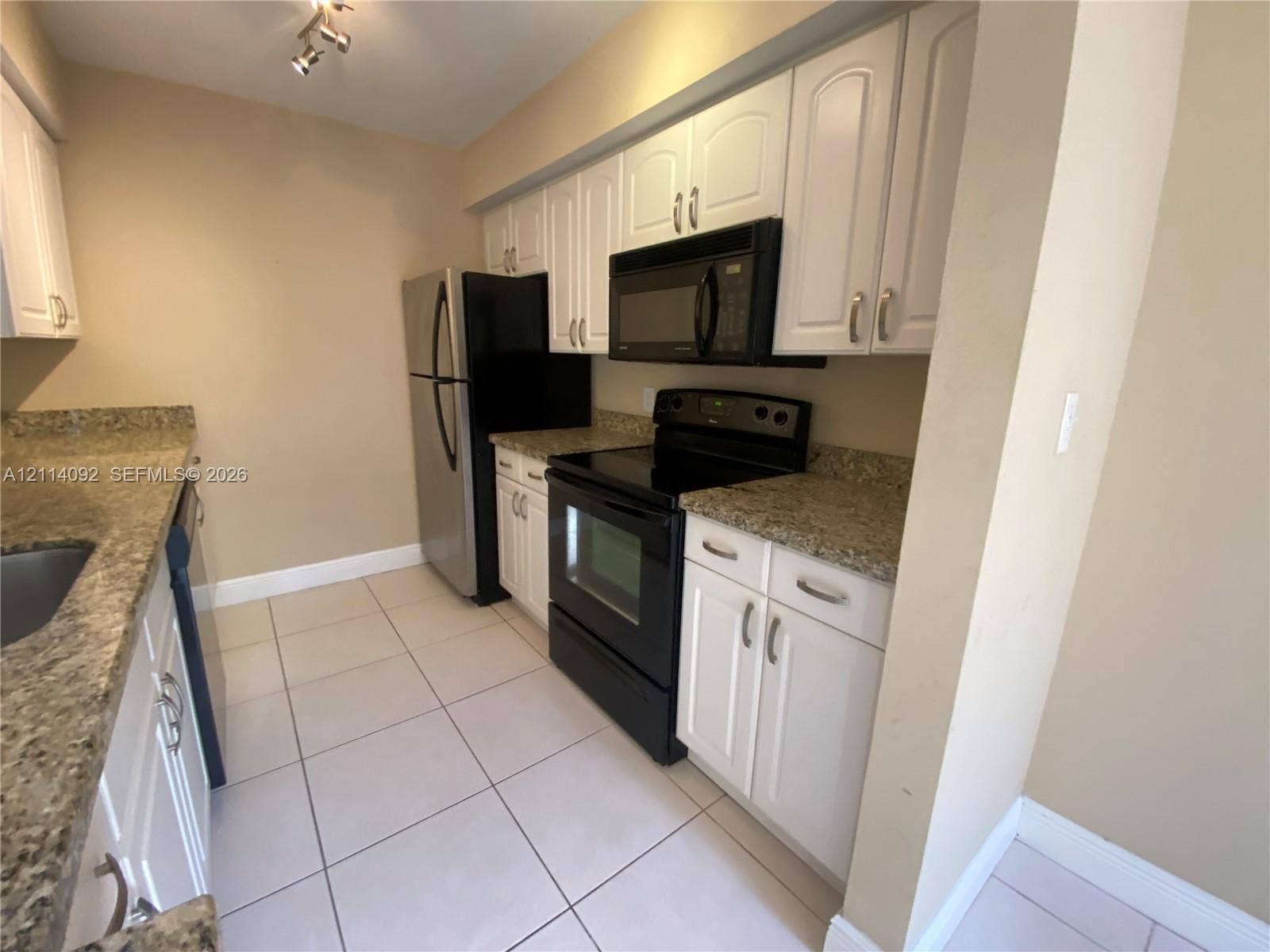 2667 NW 33rd Street, #2413, Oakland Park, Oakland Park, FL 33309 Kitchen featuring white cabinetry, stone-finish countertops, tile flooring, and integrated black appliances