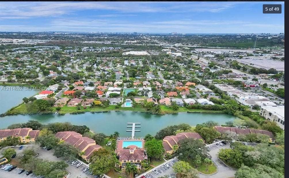 2667 NW 33rd Street, #2413, Oakland Park, Oakland Park, FL 33309 Aerial perspective of residential property featuring a waterfront location, private dock, swimming pool, tile roofing, and expansive grounds with mature landscaping