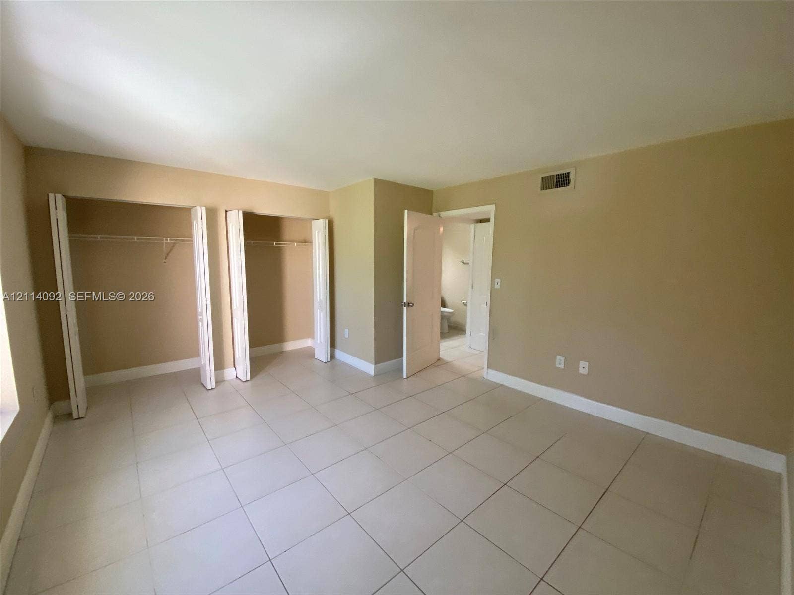 2667 NW 33rd Street, #2413, Oakland Park, Oakland Park, FL 33309 Room featuring large-format tile flooring, dual reach-in closets with bi-fold doors, and neutral wall color
