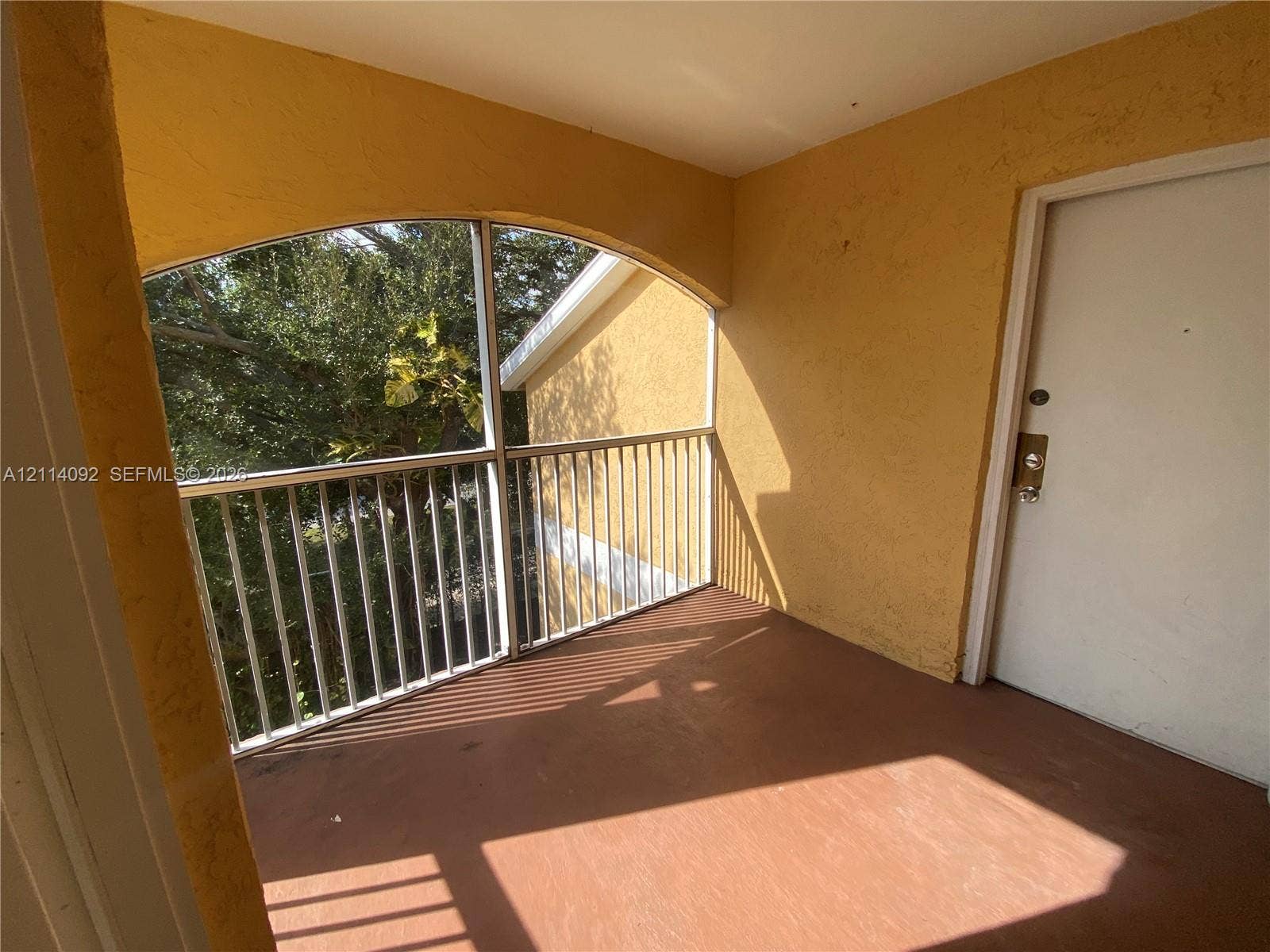 2667 NW 33rd Street, #2413, Oakland Park, Oakland Park, FL 33309 Covered balcony featuring an arched entryway, metal railing, screen enclosure, and solid surface flooring