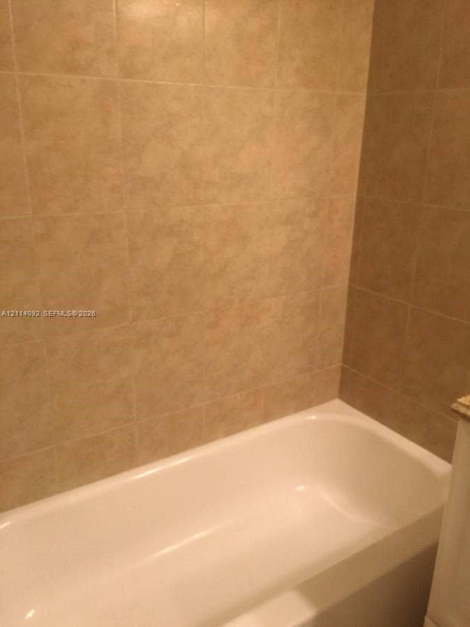 2667 NW 33rd Street, #2413, Oakland Park, Oakland Park, FL 33309 Bathtub featuring a white finish and full-height, square-format stone-tile surround