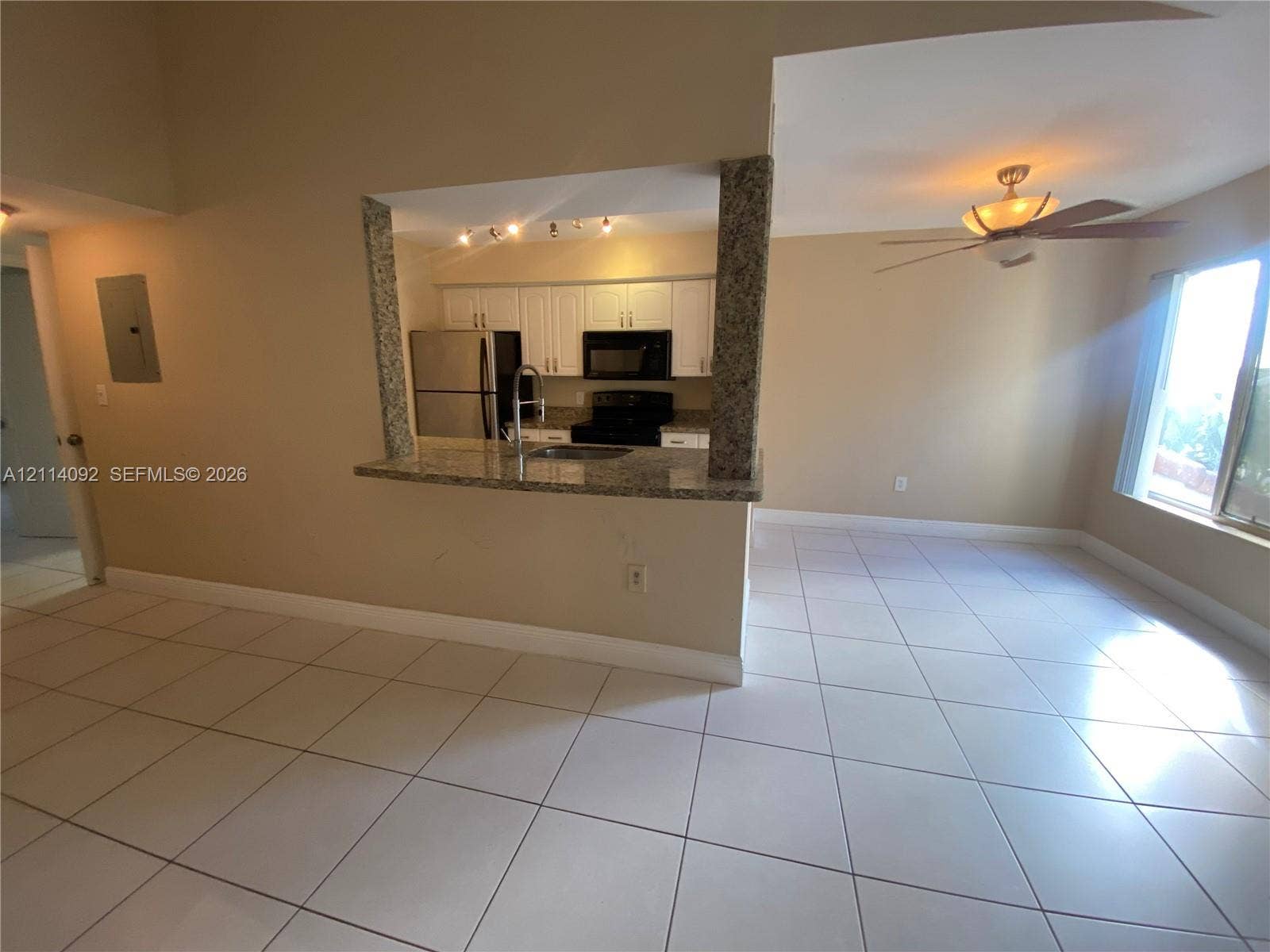 2667 NW 33rd Street, #2413, Oakland Park, Oakland Park, FL 33309 Kitchen featuring a stone-topped breakfast bar, white cabinetry, integrated stainless steel appliances, tile flooring, and a ceiling fan with light fixture