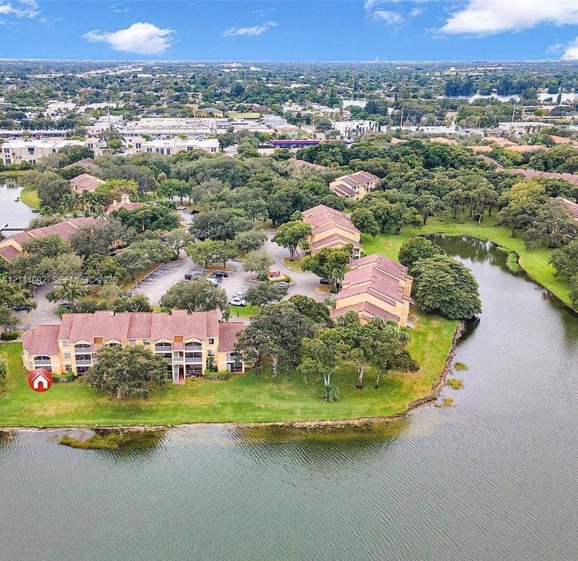 2667 NW 33rd Street, #2413, Oakland Park, Oakland Park, FL 33309 Multi-story residential buildings featuring tile roofs, private balconies, paved parking areas, and expansive water frontage surrounded by mature trees