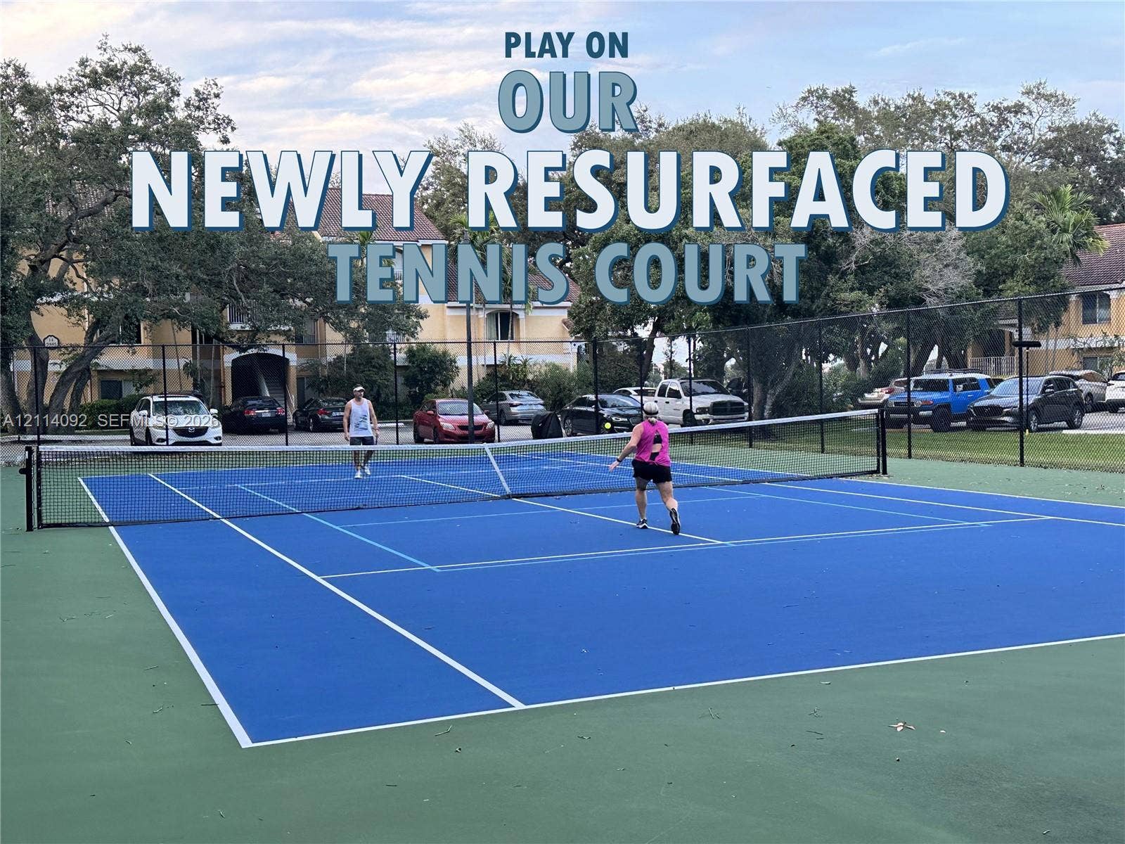 2667 NW 33rd Street, #2413, Oakland Park, Oakland Park, FL 33309 Tennis court featuring a high-contrast blue and green surface, permanent net, and perimeter chain-link fencing
