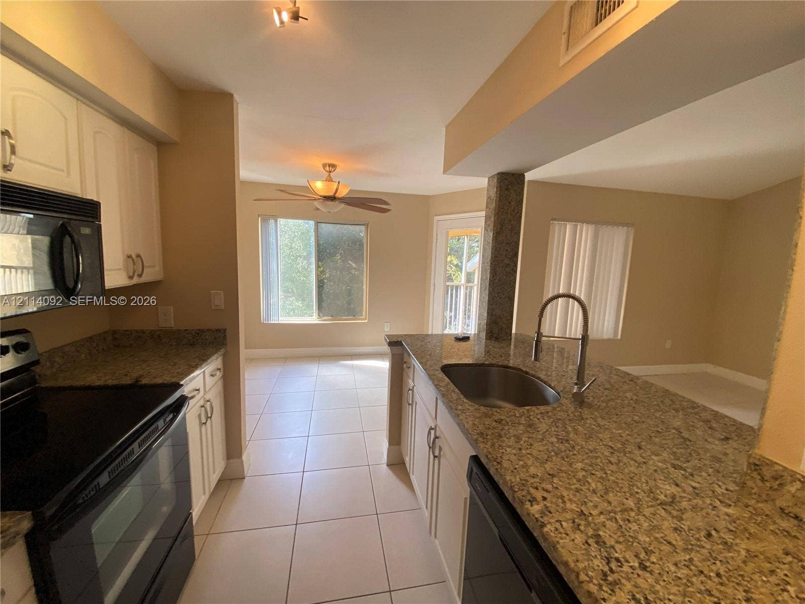 2667 NW 33rd Street, #2413, Oakland Park, Oakland Park, FL 33309 Kitchen featuring stone countertops, white cabinetry, tile flooring, an undermount stainless steel sink with a goose-neck faucet, and built-in black appliances