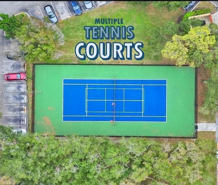 2667 NW 33rd Street, #2413, Oakland Park, Oakland Park, FL 33309 Tennis court featuring a multi-color surface, perimeter fencing, and surrounding mature trees