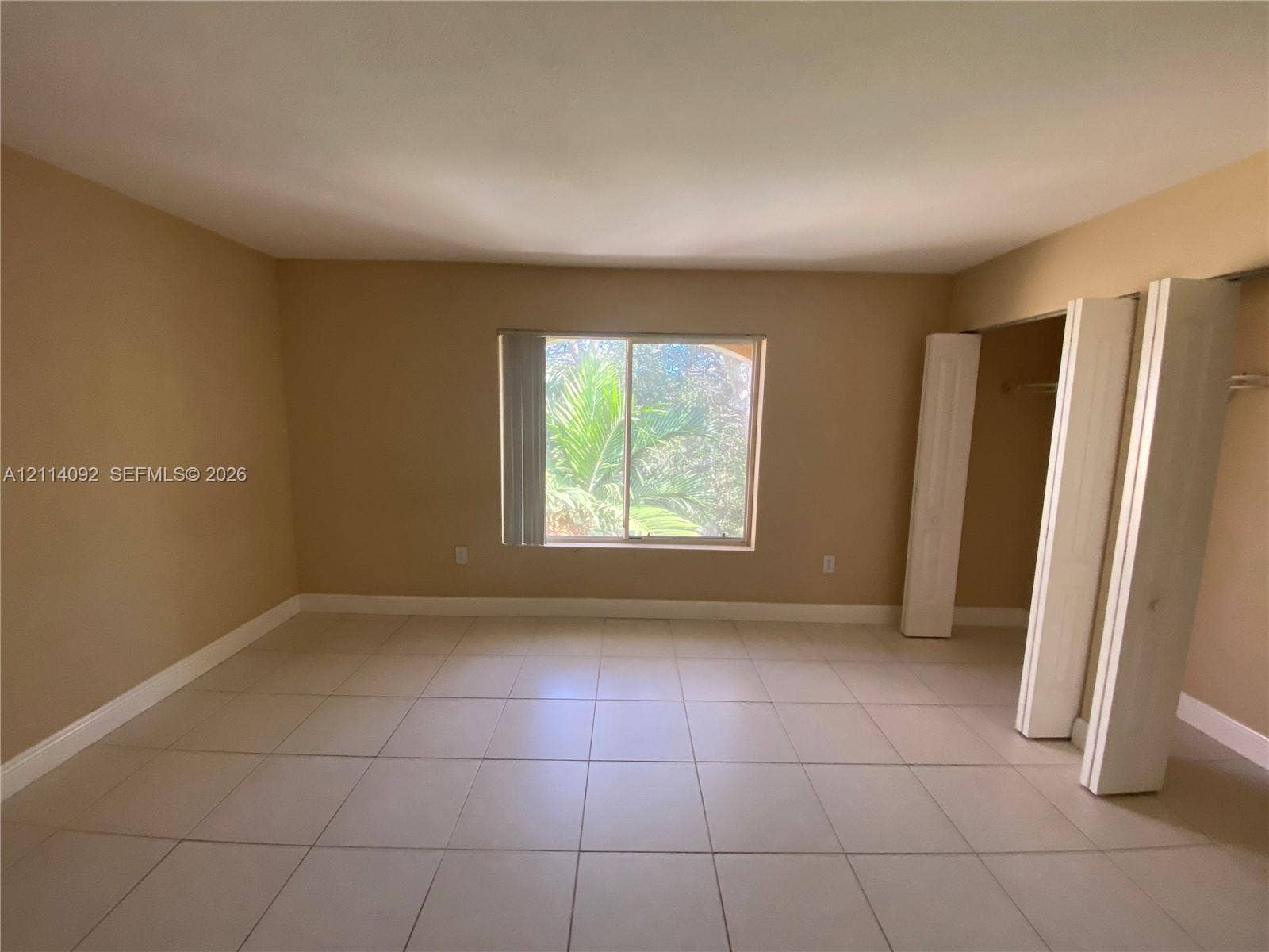 2667 NW 33rd Street, #2413, Oakland Park, Oakland Park, FL 33309 Neutral-toned interior featuring large-format ceramic floor tile, a central sliding window, and built-in closet storage with bi-fold doors