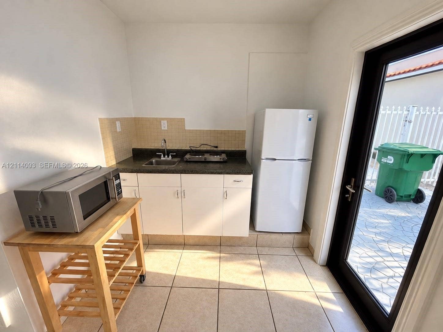 4916 SW 142nd Place, #4916, Miami, Miami, FL 33175 Kitchenette featuring white cabinetry, dark stone-finish countertops, tile backsplash, and ceramic floor tiling