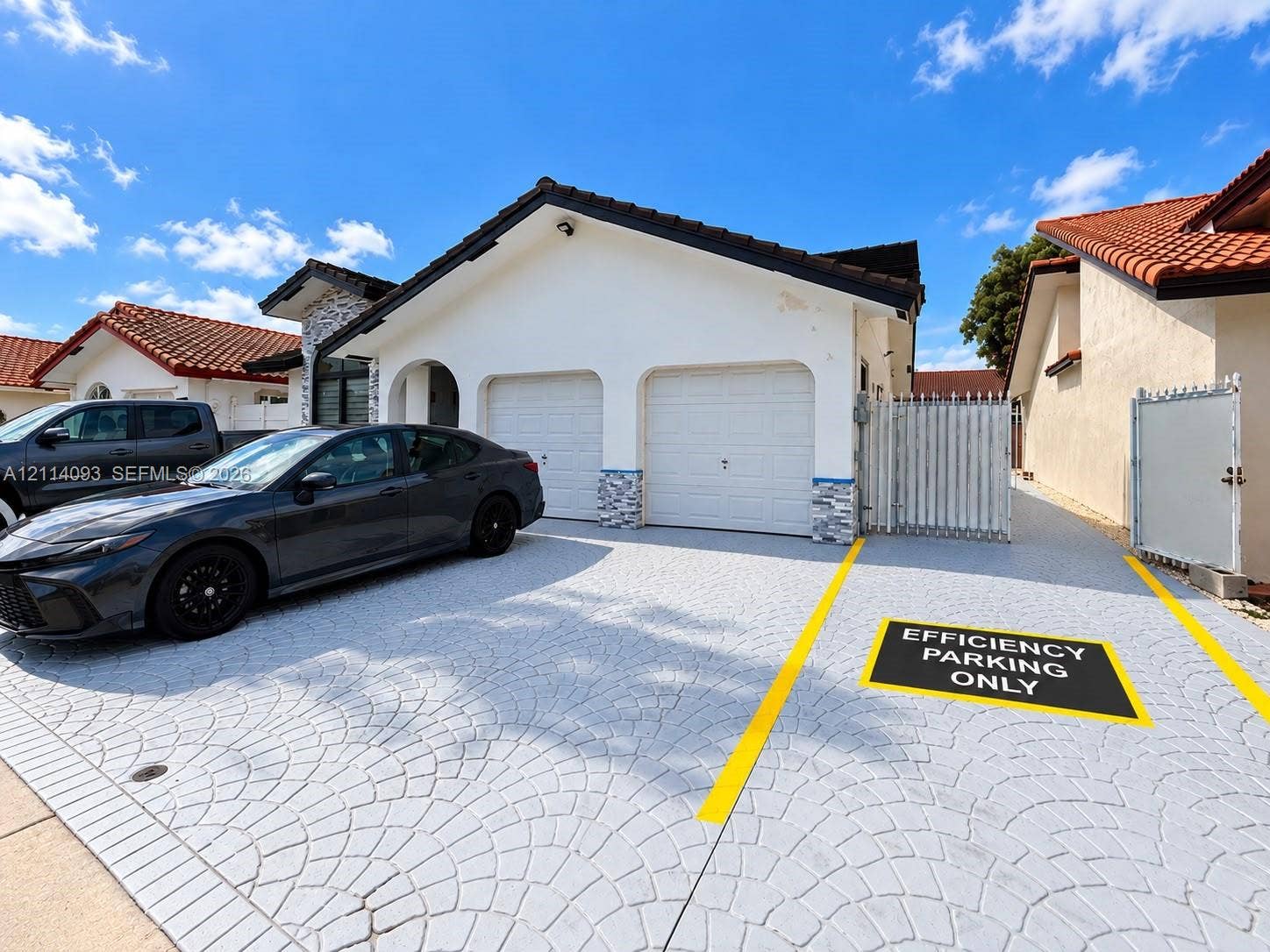 4916 SW 142nd Place, #4916, Miami, Miami, FL 33175 Stucco exterior featuring a two-car garage, patterned concrete driveway, stone facade accents, and a metal privacy gate