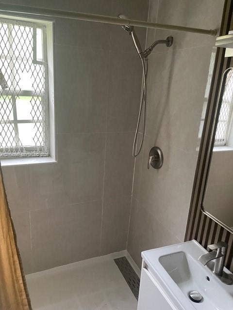 14180 NW 22nd Court, #0, Opa Locka, Opa Locka, FL 33054 Bathroom featuring a tiled shower enclosure with a handheld showerhead, a single-basin vanity with a chrome faucet, and a window with security screening