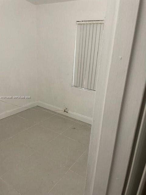 14180 NW 22nd Court, #0, Opa Locka, Opa Locka, FL 33054 Neutral interior room featuring large-format tile flooring, white wall finishes, and a single window with vertical blinds